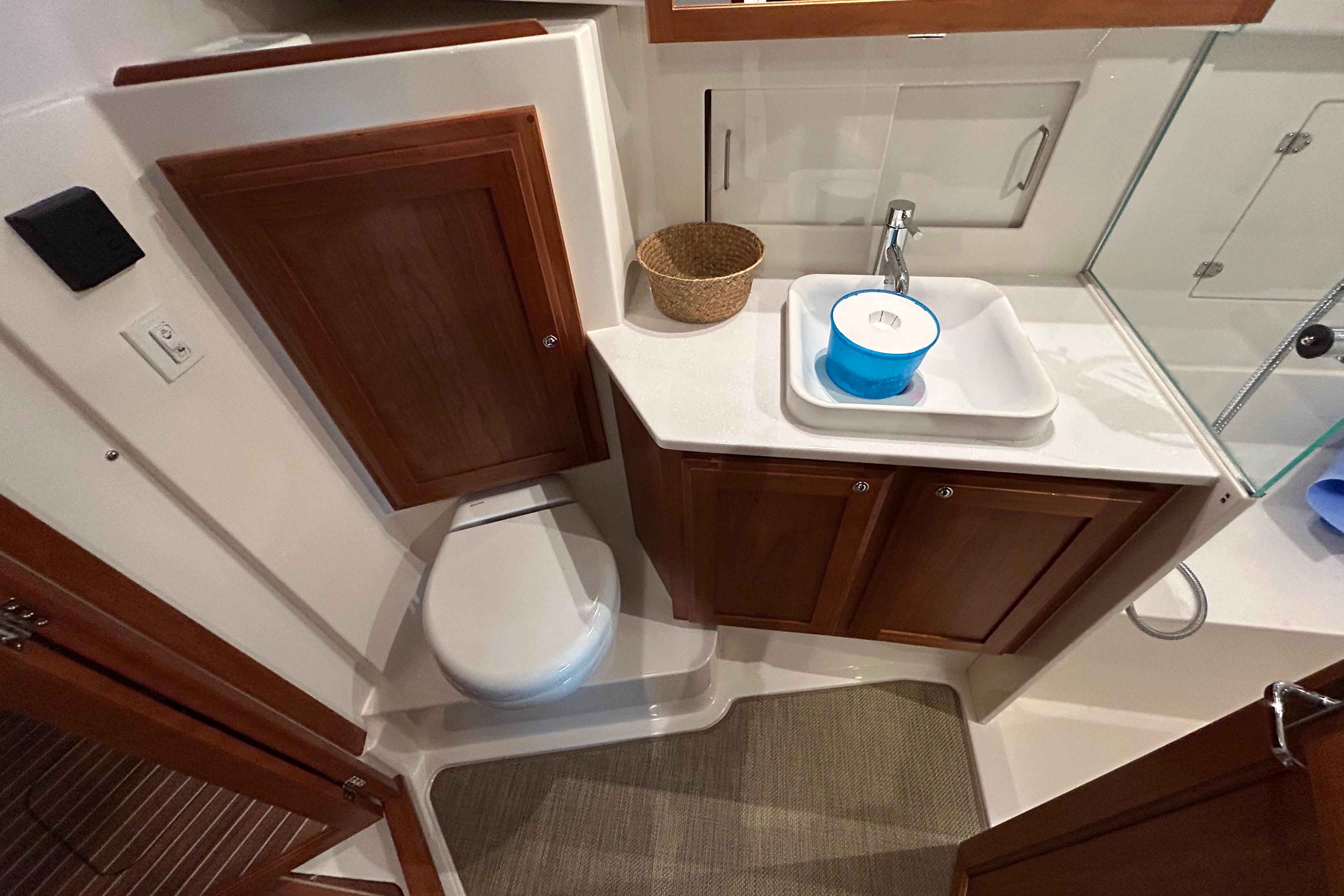 2023 Back Cove 39O yacht bathroom with wooden cabinets, sink, and toilet.