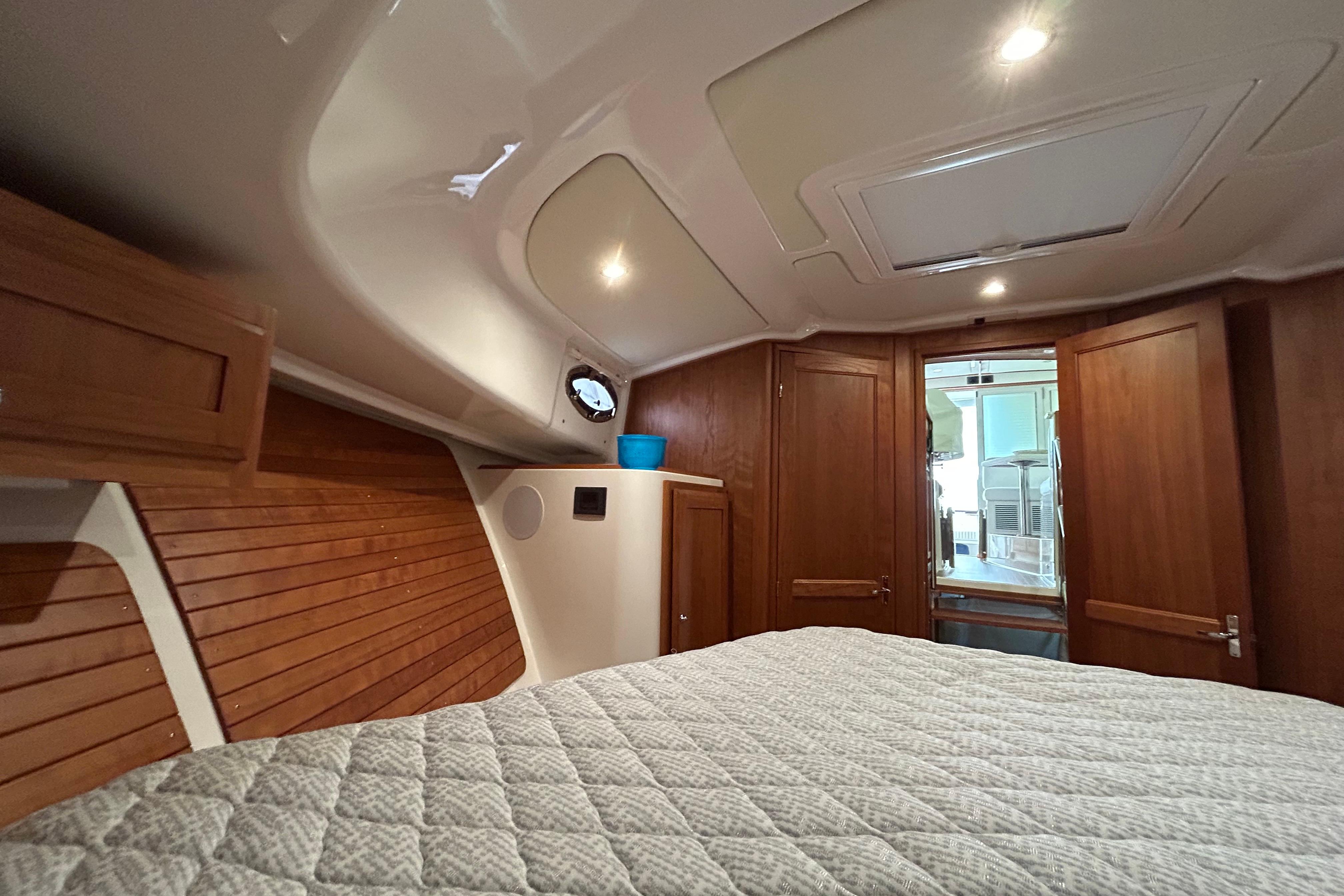 2023 Back Cove 39O cabin interior with wood paneling and cozy bedding.