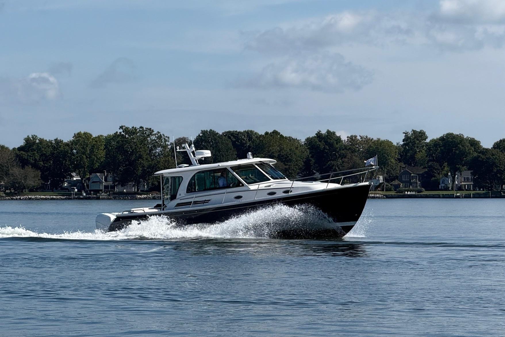 2023 Back Cove 39O cruising on a serene lake with lush green shoreline.