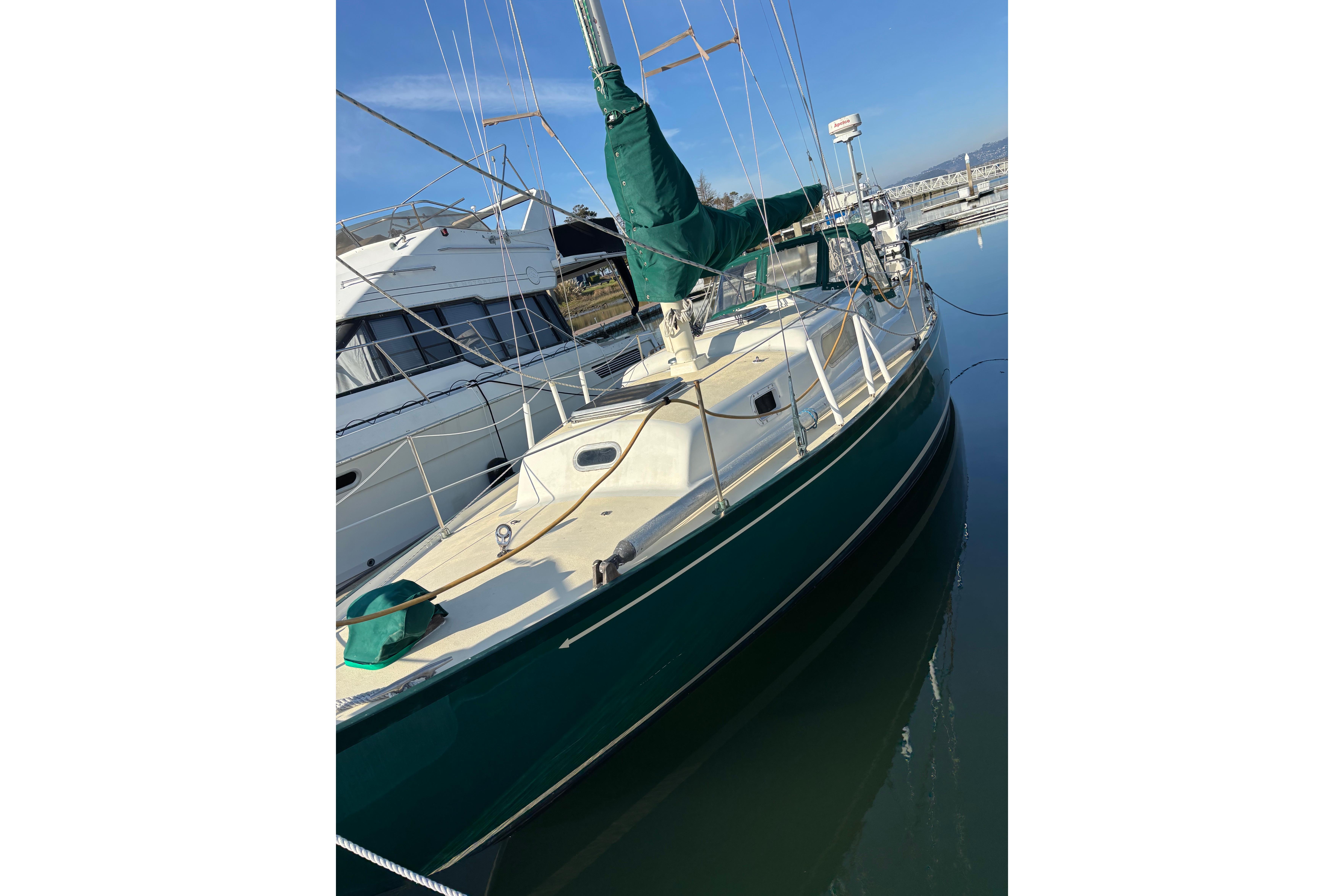 1968 Spencer 35 sailboat docked, green hull, white deck, marina background.