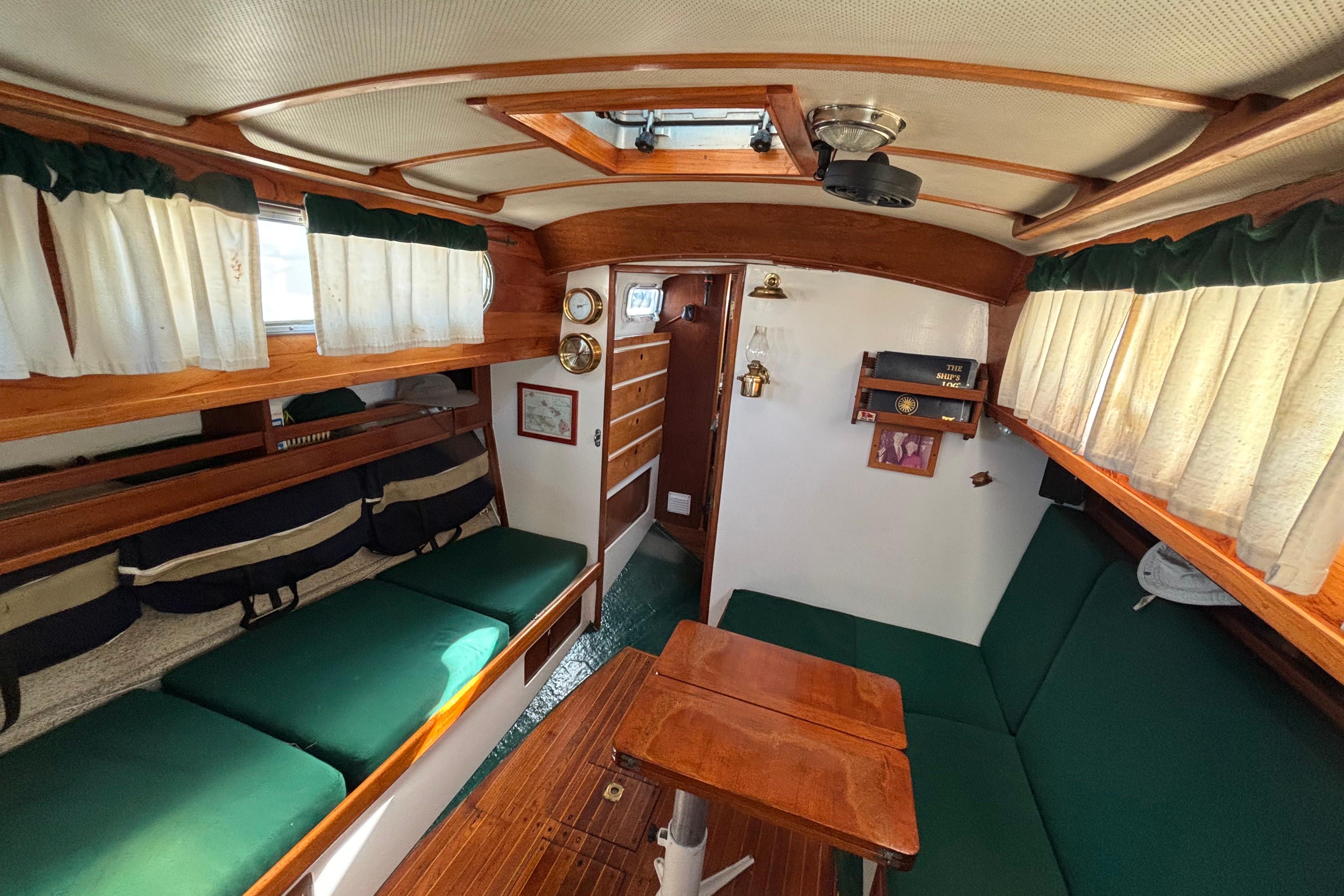 Interior of a 1968 Spencer 35 sailboat with wooden furnishings and green seating.