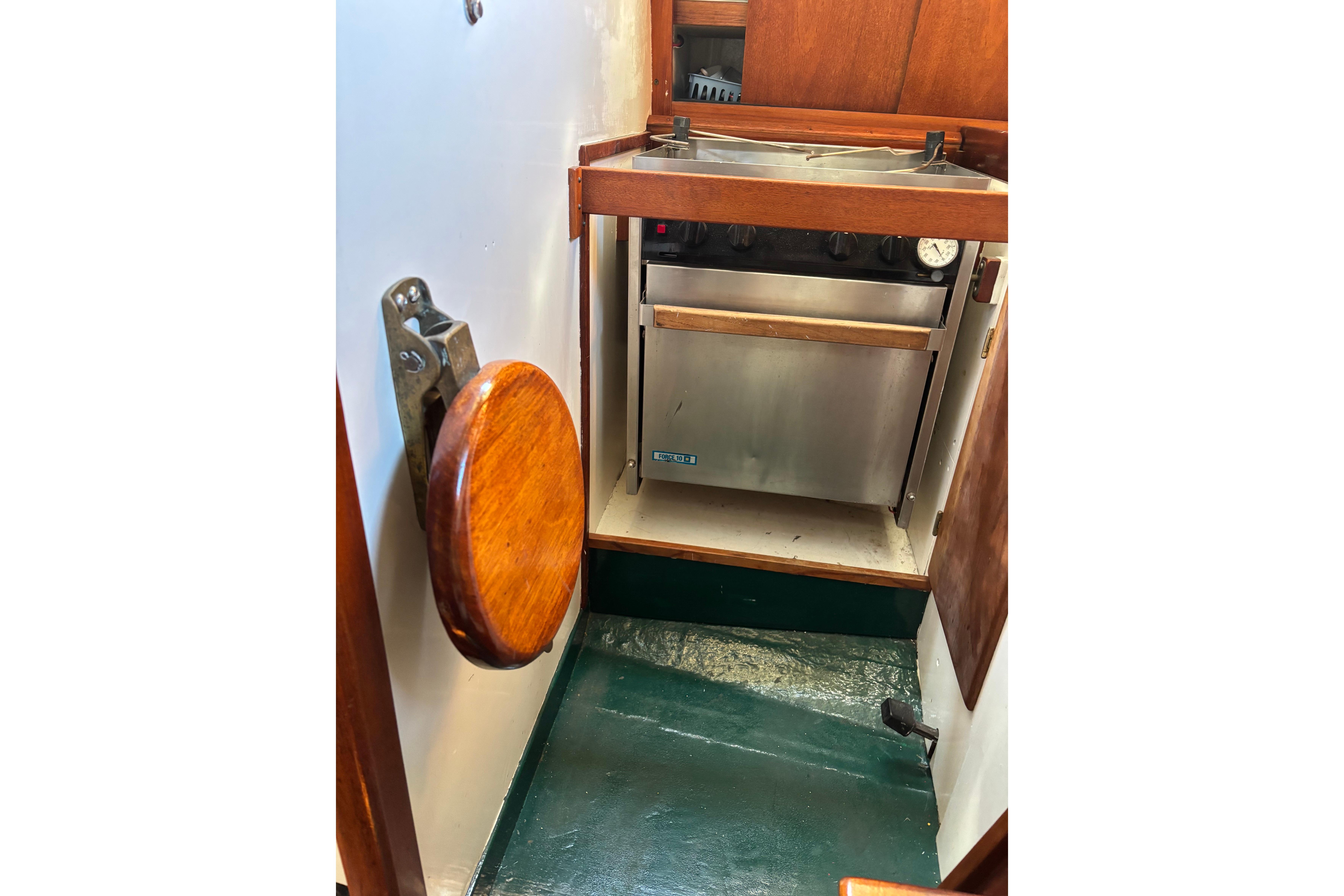 Compact kitchen area in a 1968 Spencer 35 boat, featuring a stainless steel stove.