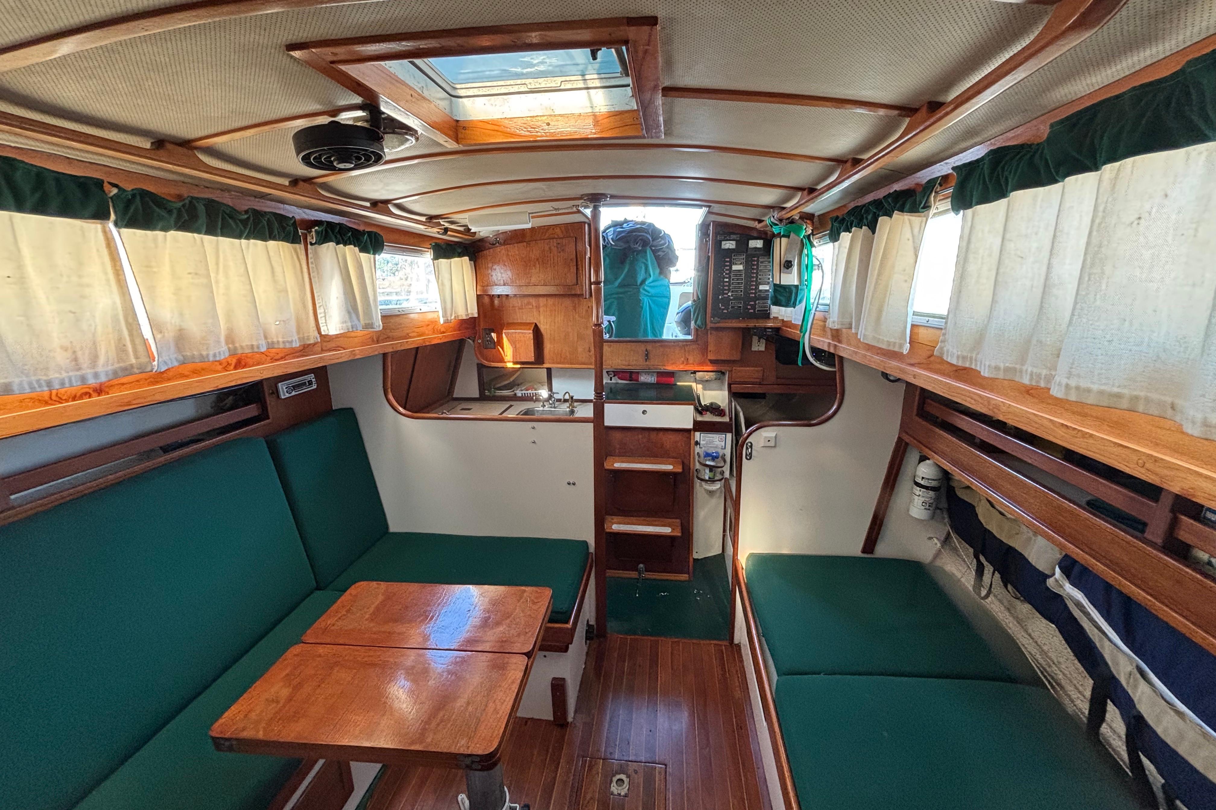 Interior of a 1968 Spencer 35 sailboat with green seating and wooden accents.