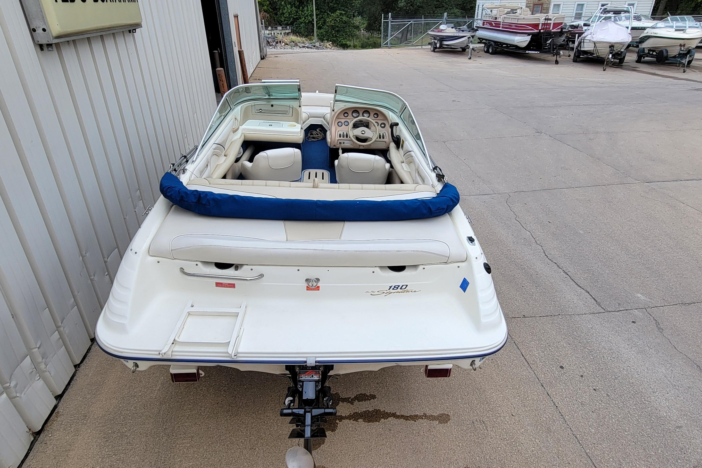 1994 Sea Ray 180 Bow Rider boat, white exterior, parked near a building with other boats.