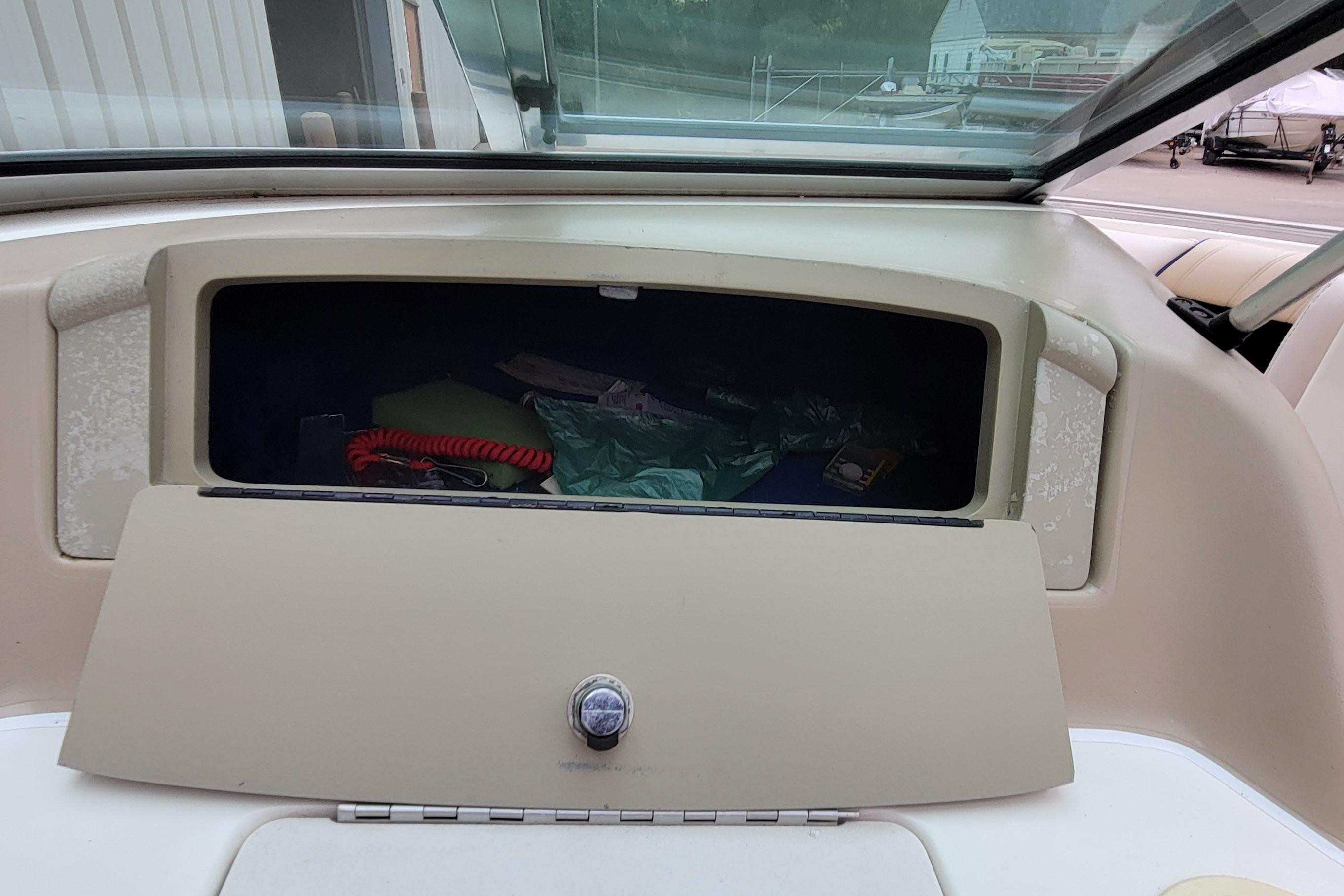 1994 Sea Ray 180 Bow Rider glove compartment with open storage, showing various items.