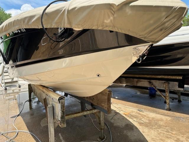 2011 Chaparral 216 SSi boat on stand, covered, with black and white hull.