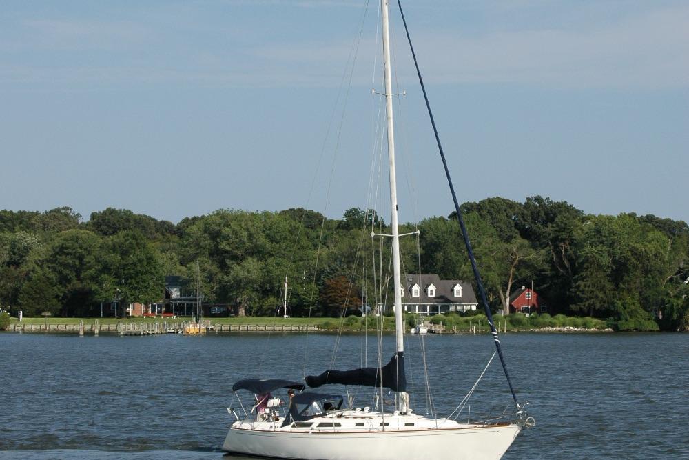 Sailboat Sabre 38 MkII (1988) on a serene lake with lush green shoreline.