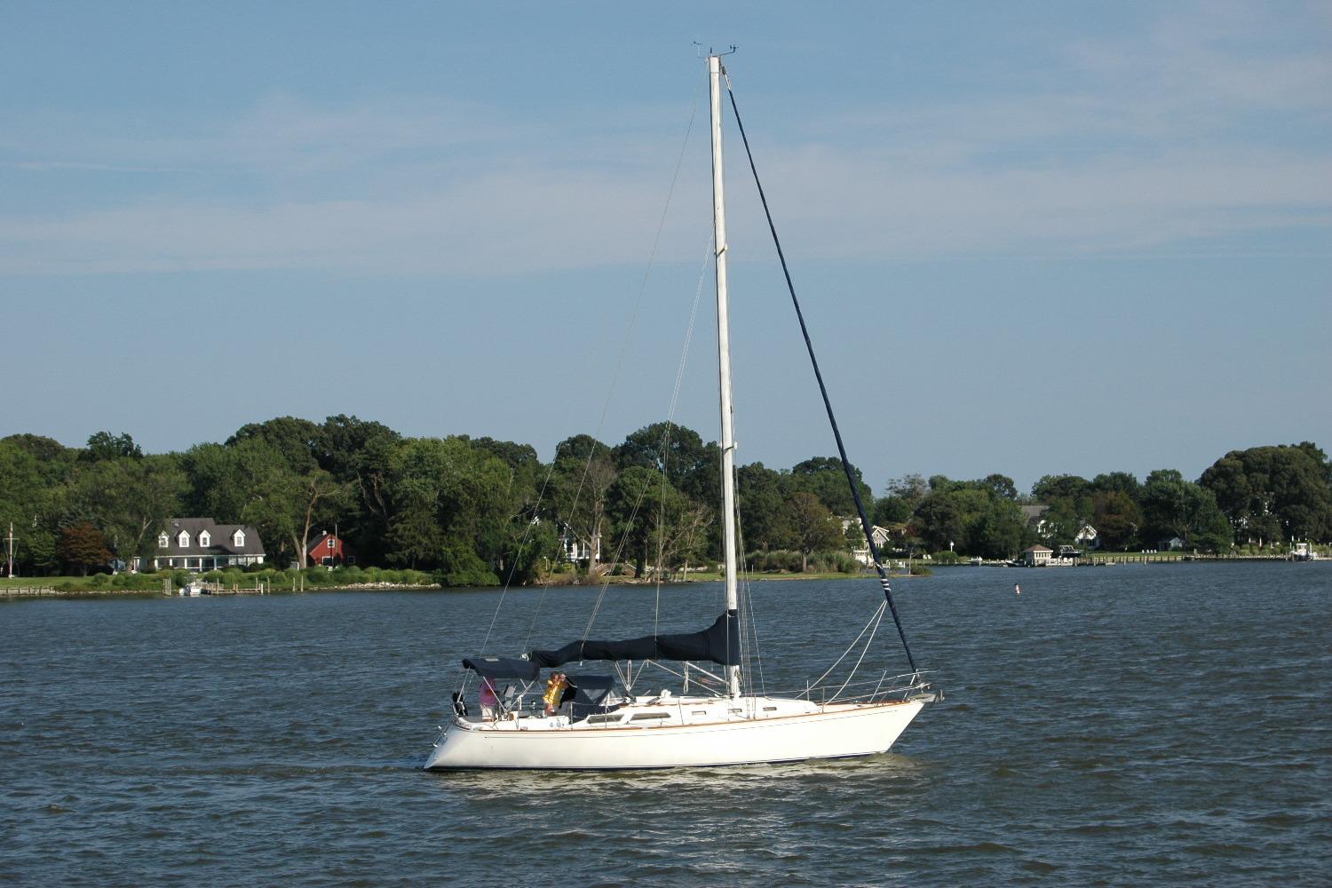 1988 Sabre 38 MkII sailboat on calm water with scenic shoreline background.