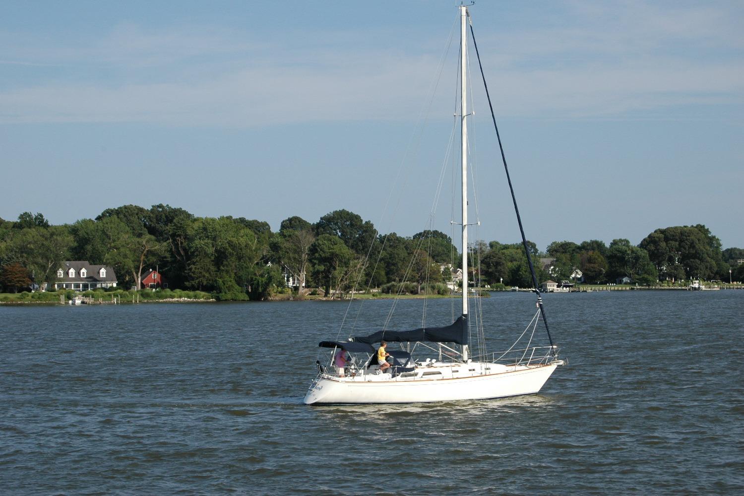 1988 Sabre 38 MkII sailboat on calm water with scenic shoreline background.