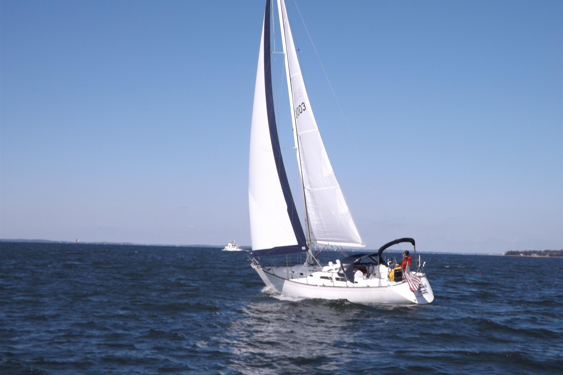 1988 Sabre 38 MkII sailboat gliding on open water under clear blue skies.