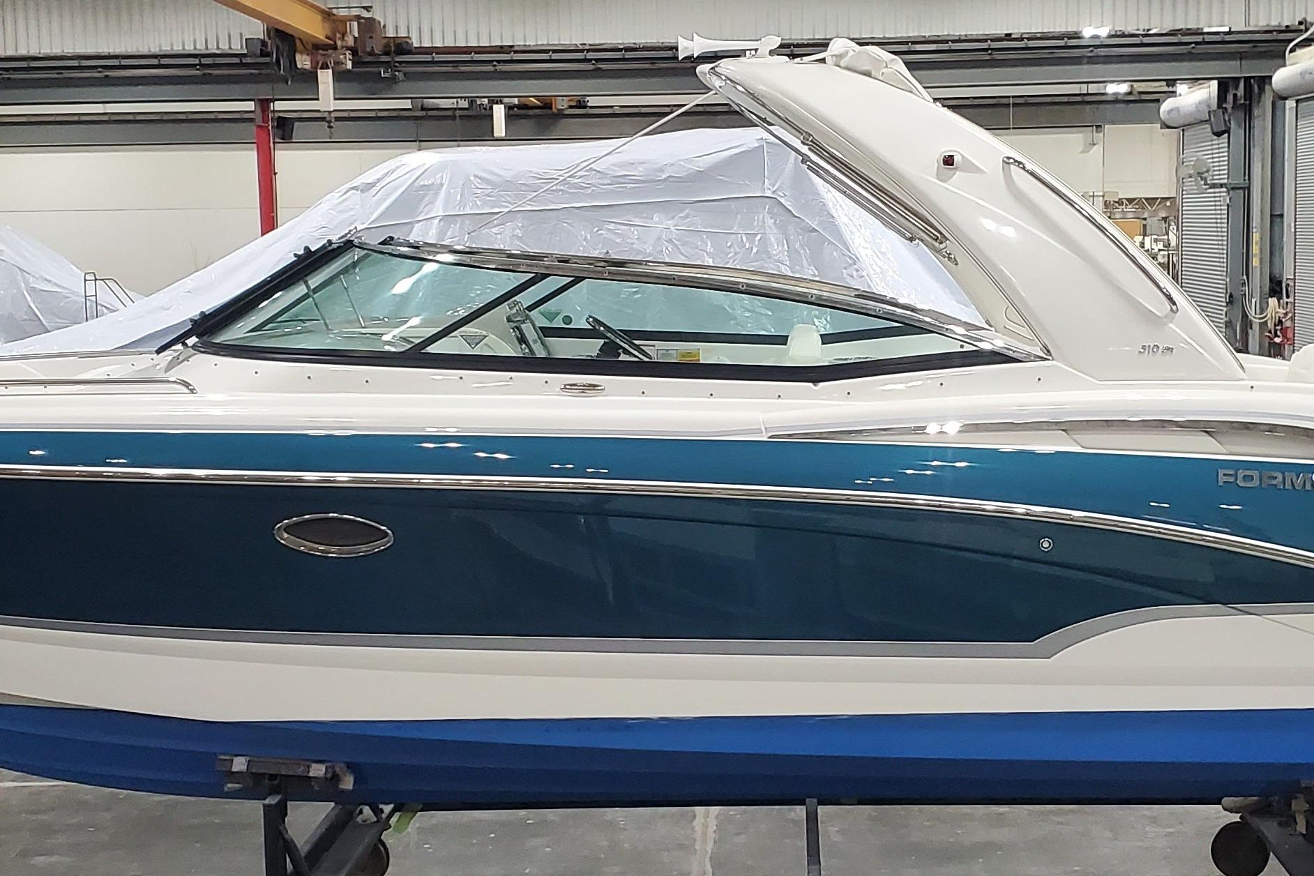 2009 Formula 310 Bowrider boat in a warehouse, featuring sleek blue and white design.