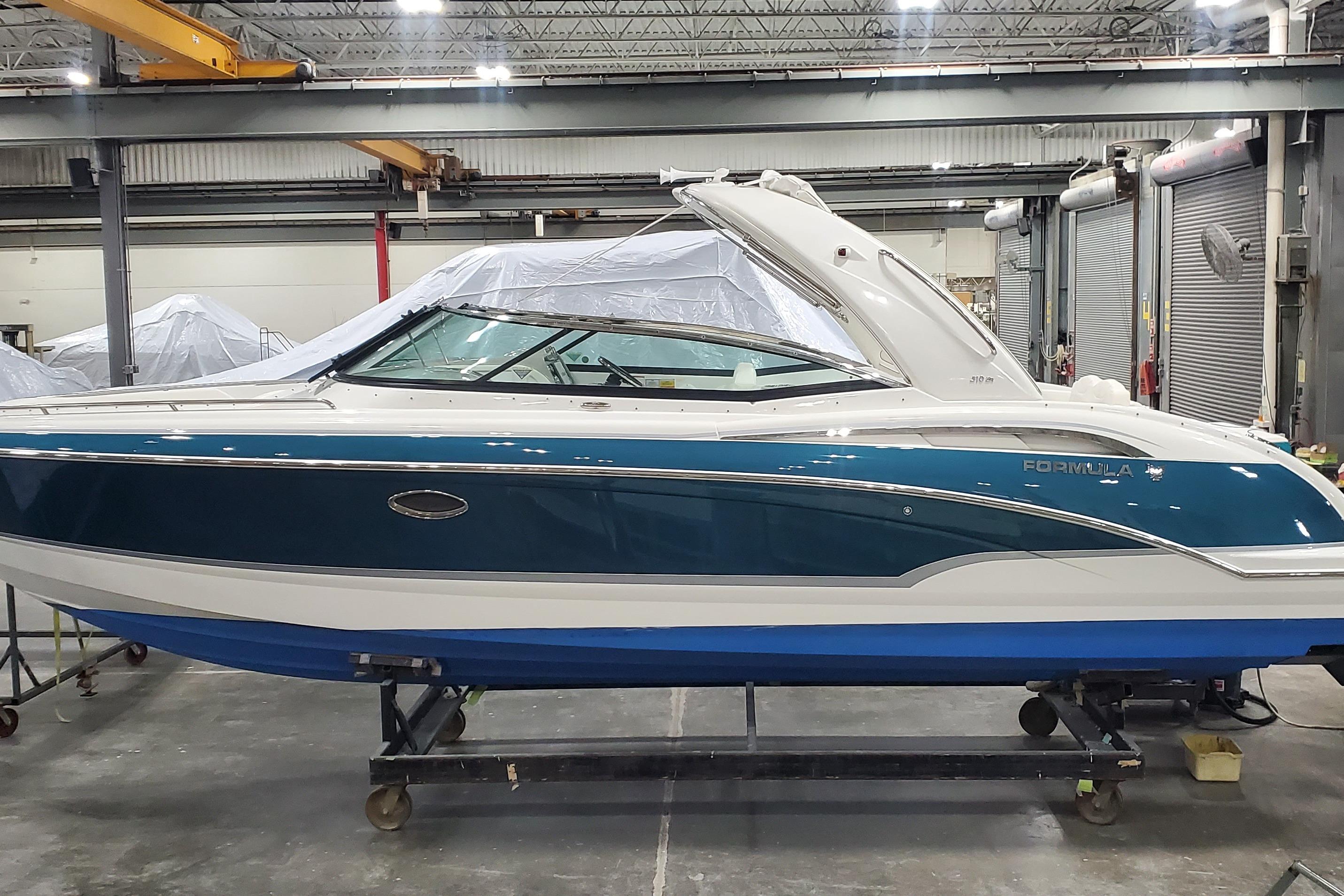 2009 Formula 310 Bowrider boat in a warehouse, blue and white exterior.