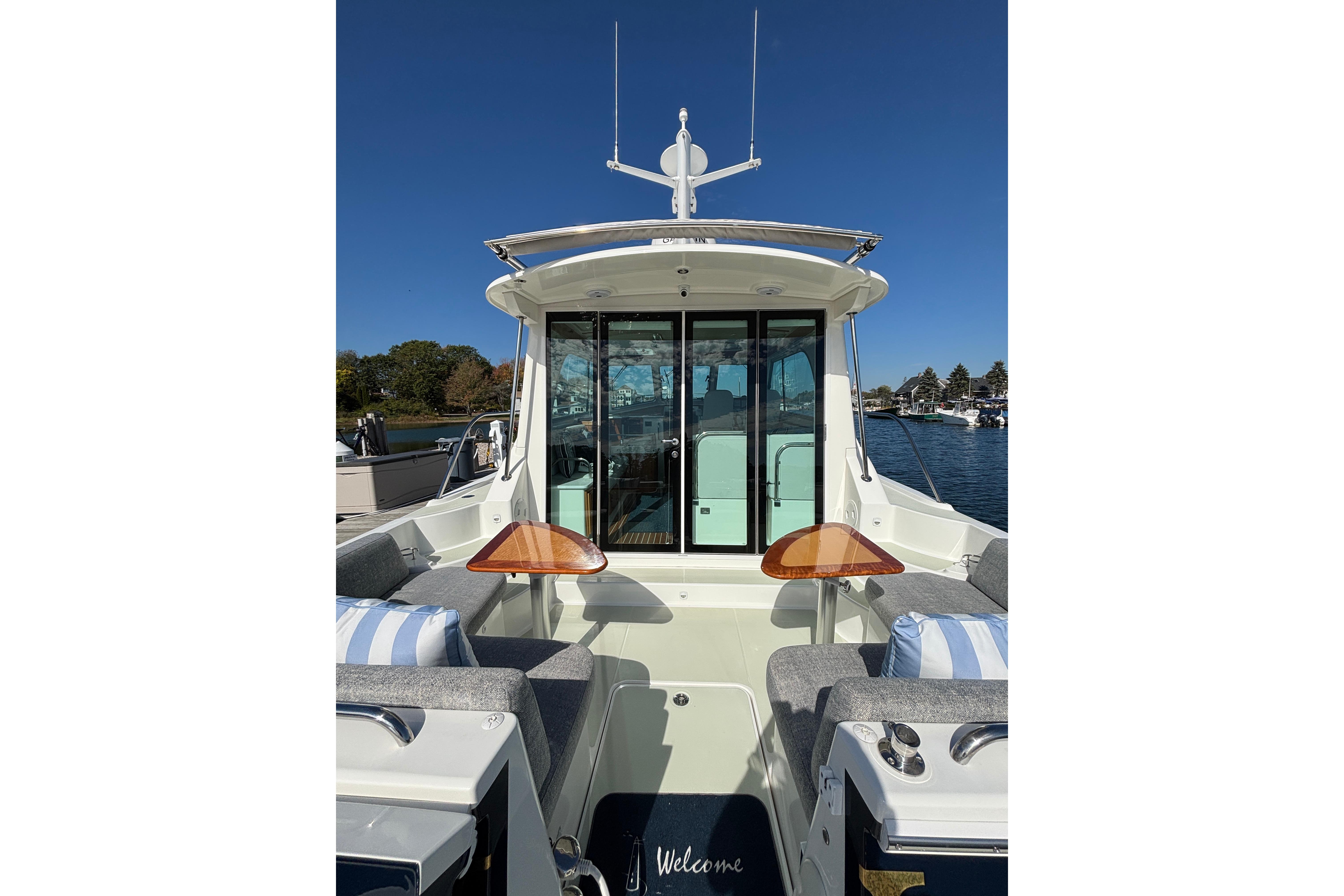 2020 Back Cove 37 boat with outdoor seating and wooden tables, docked under clear blue sky.