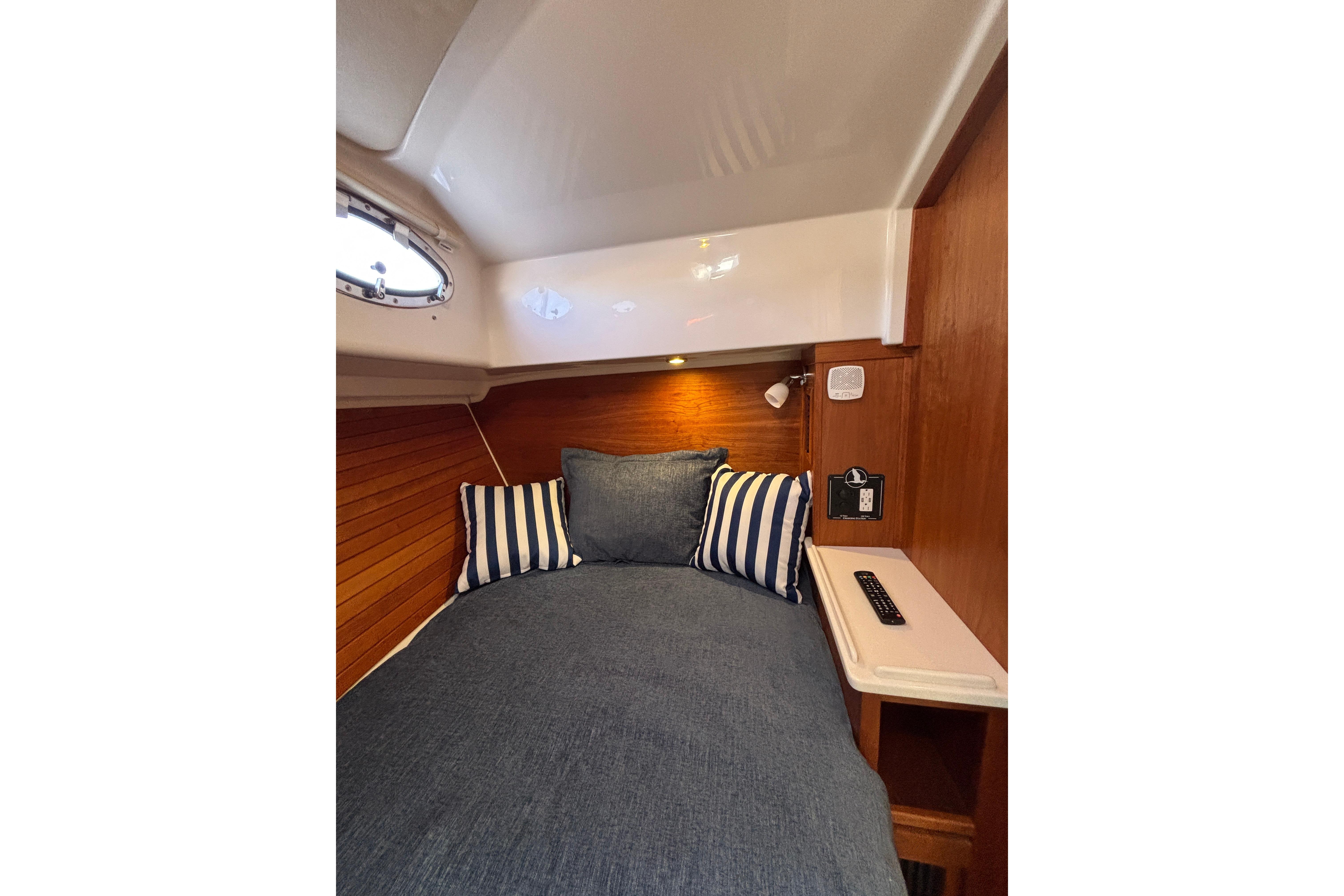 Cozy cabin interior of 2020 Back Cove 37 with striped pillows and wooden accents.