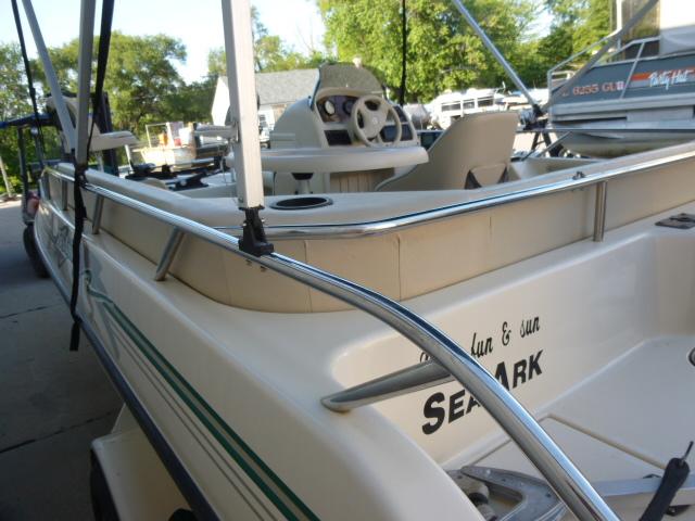 2000 SeaArk Sunstar 21 boat with steering wheel and seating, docked outdoors.