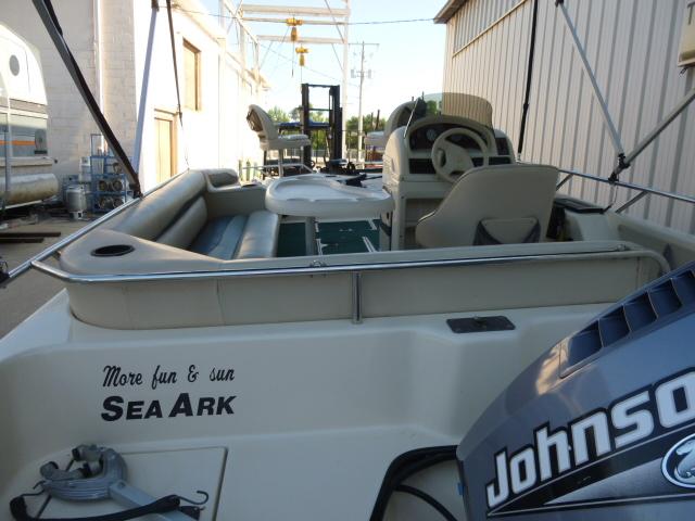2000 SeaArk Sunstar 21 boat with Johnson motor, docked near a building.