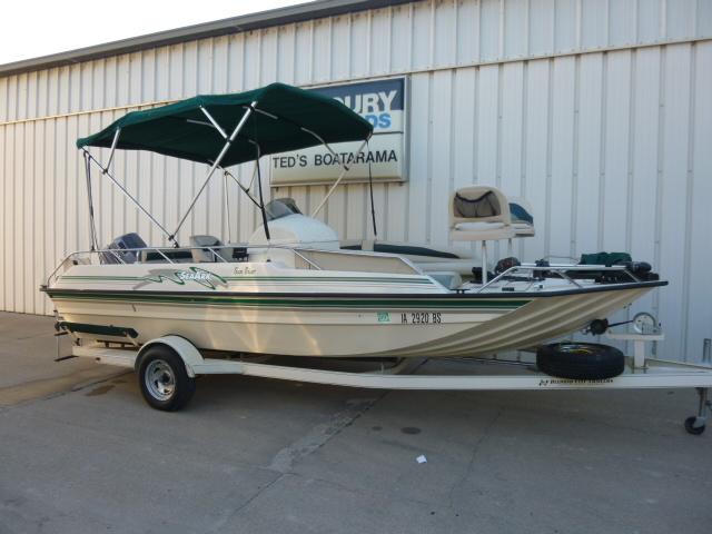 2000 SeaArk Sunstar 21 boat with canopy on trailer, parked outside a building.