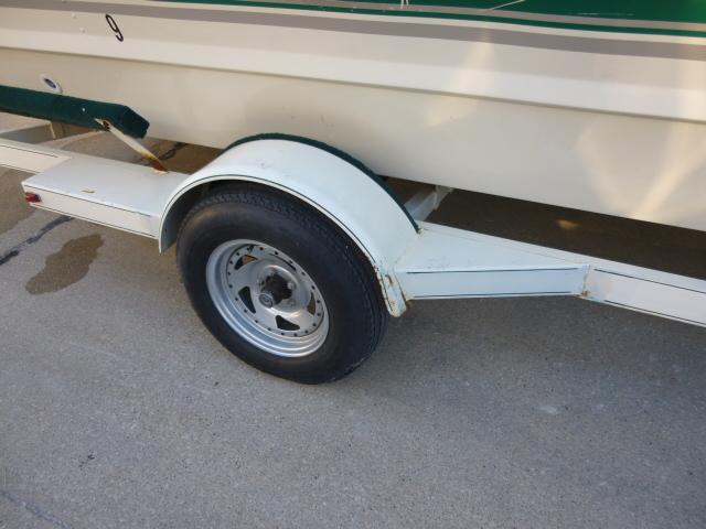 Trailer wheel of a 2000 SeaArk Sunstar 21 boat on pavement.