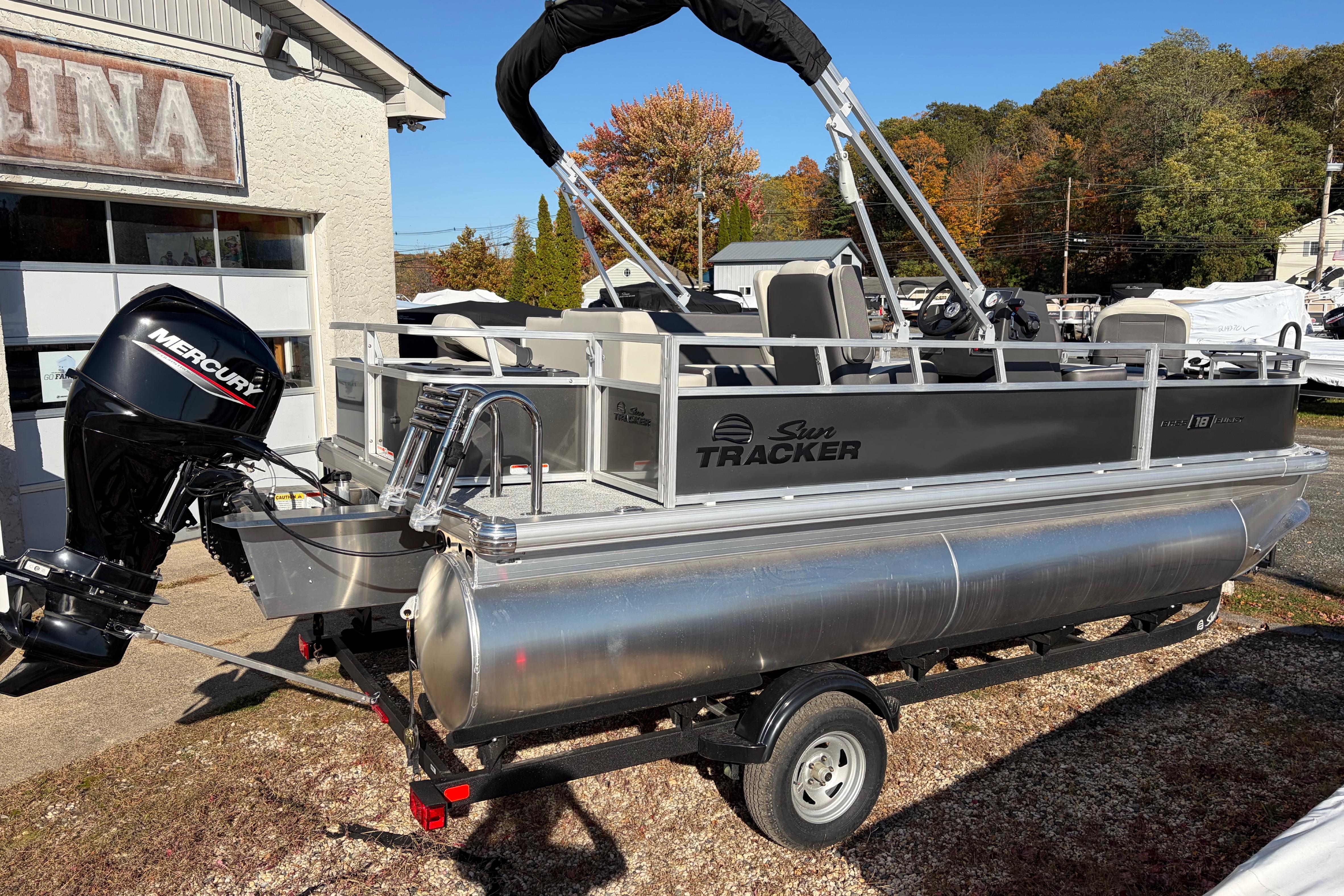2026 Sun Tracker Bass Buggy 18 DLX pontoon boat with Mercury outboard motor, parked outdoors.