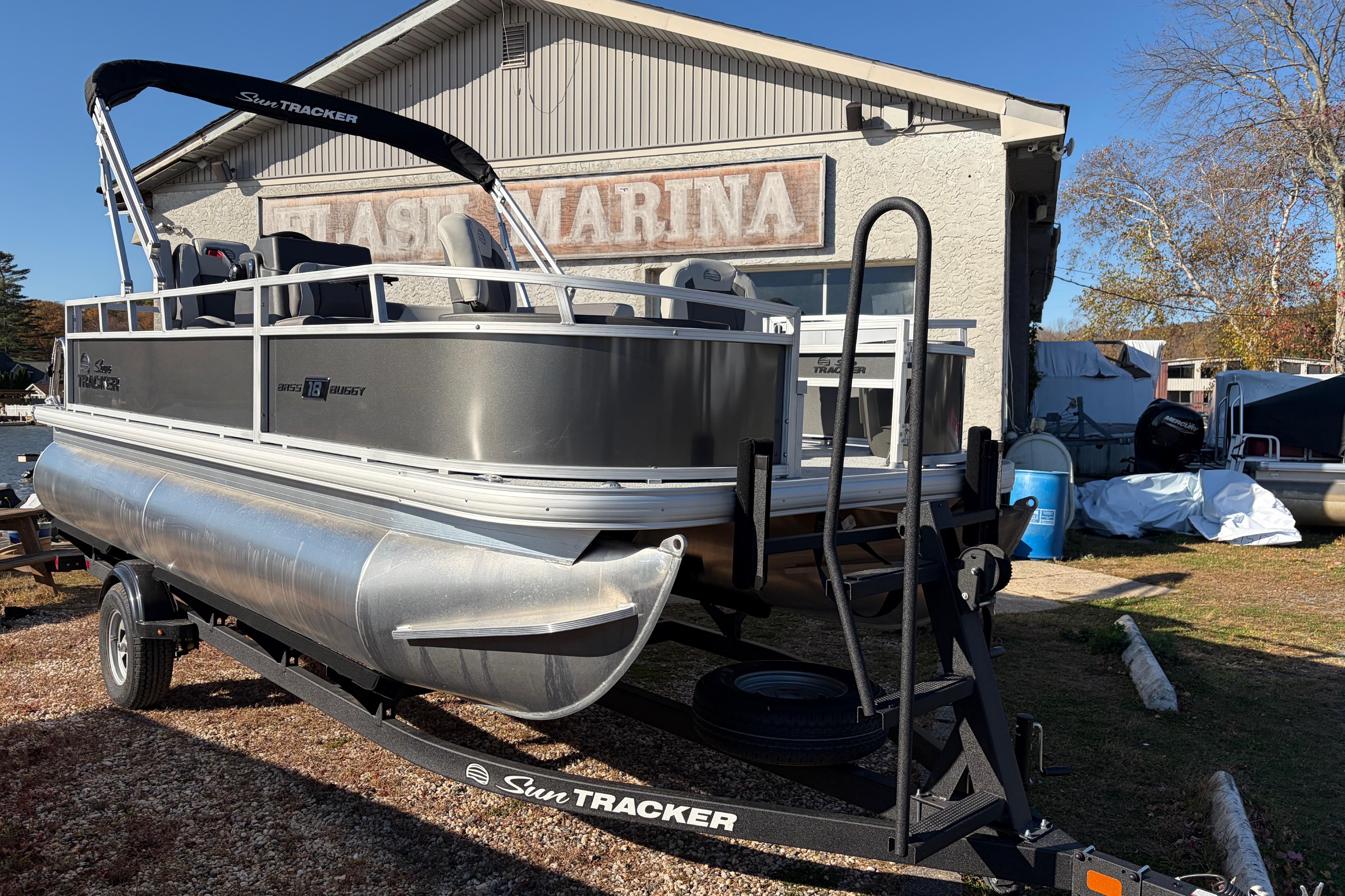 2026 Sun Tracker Bass Buggy 18 DLX pontoon boat on trailer at marina.