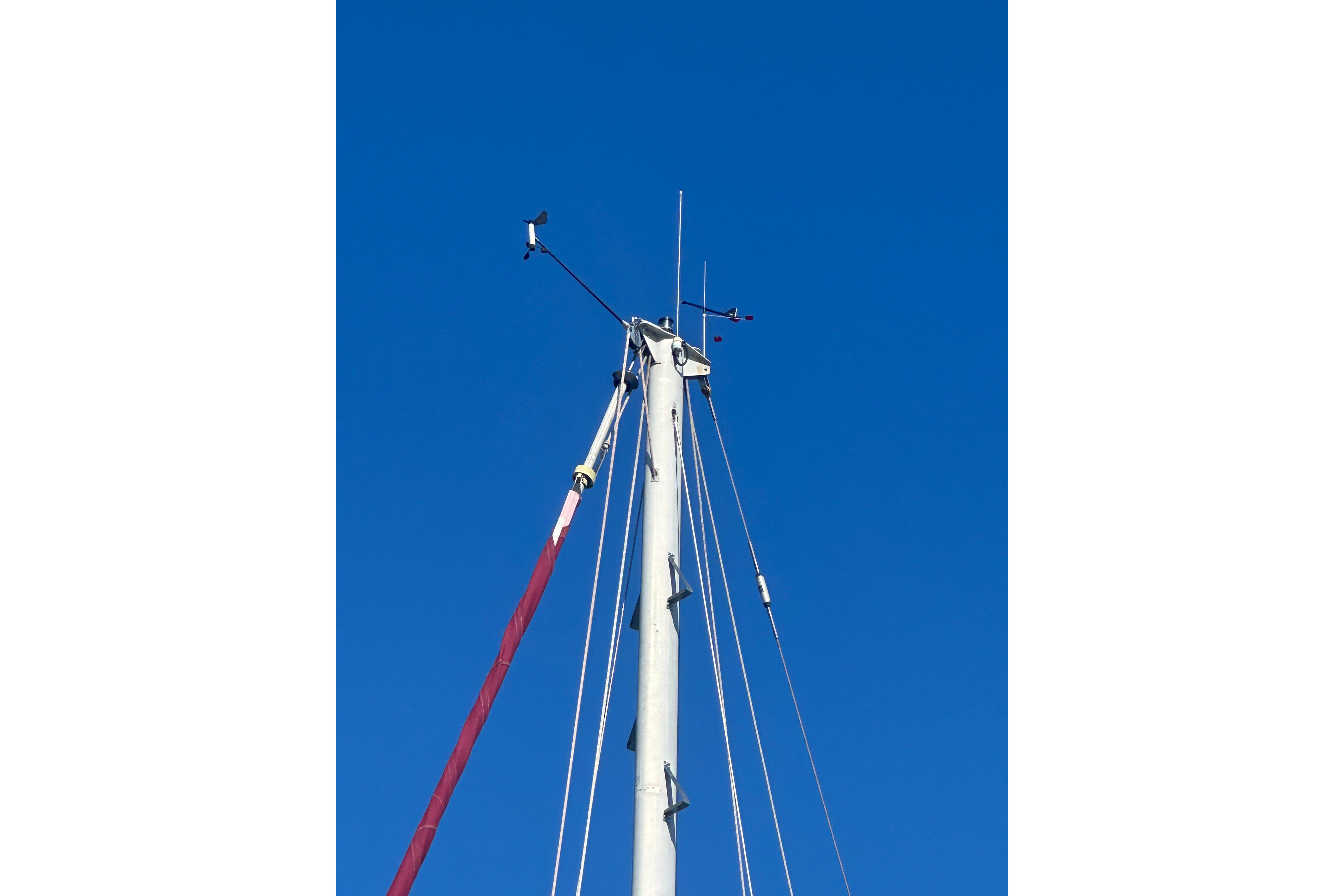 Mast of 1978 Tayana 37 sailboat against clear blue sky.