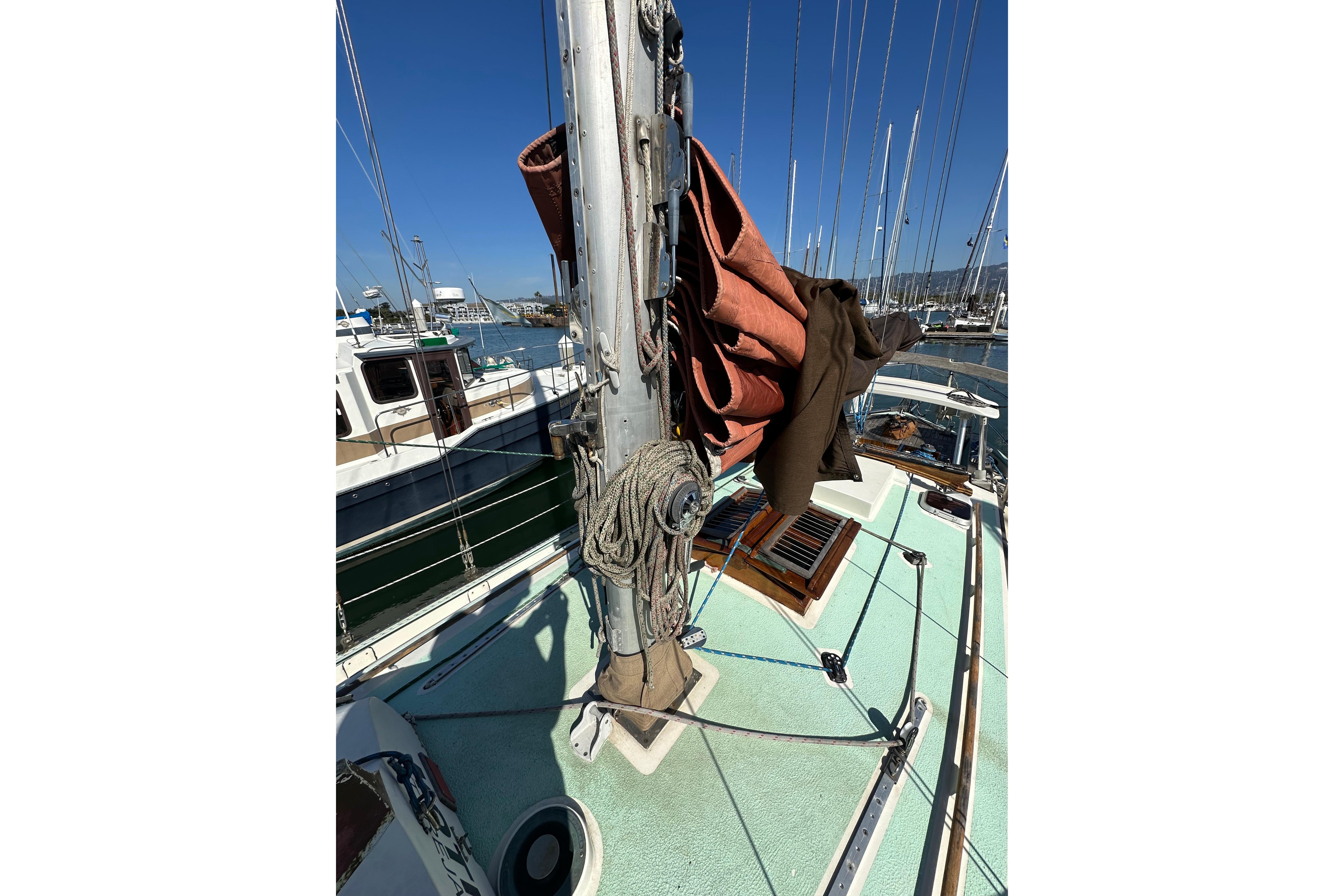 1978 Tayana 37 sailboat deck with mast, ropes, and sails in a marina.