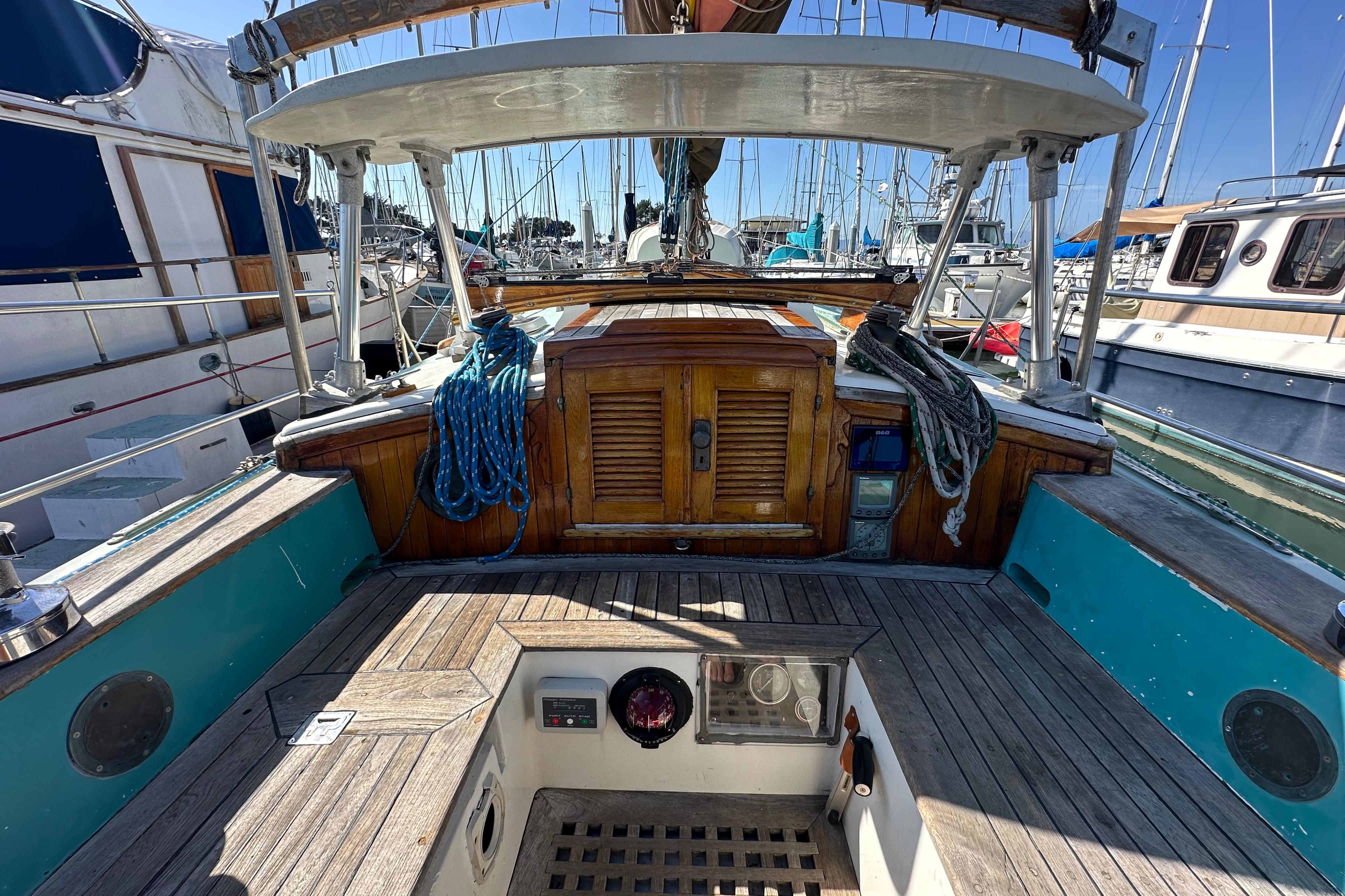 Cockpit of a 1978 Tayana 37 sailboat with wooden accents and nautical ropes.