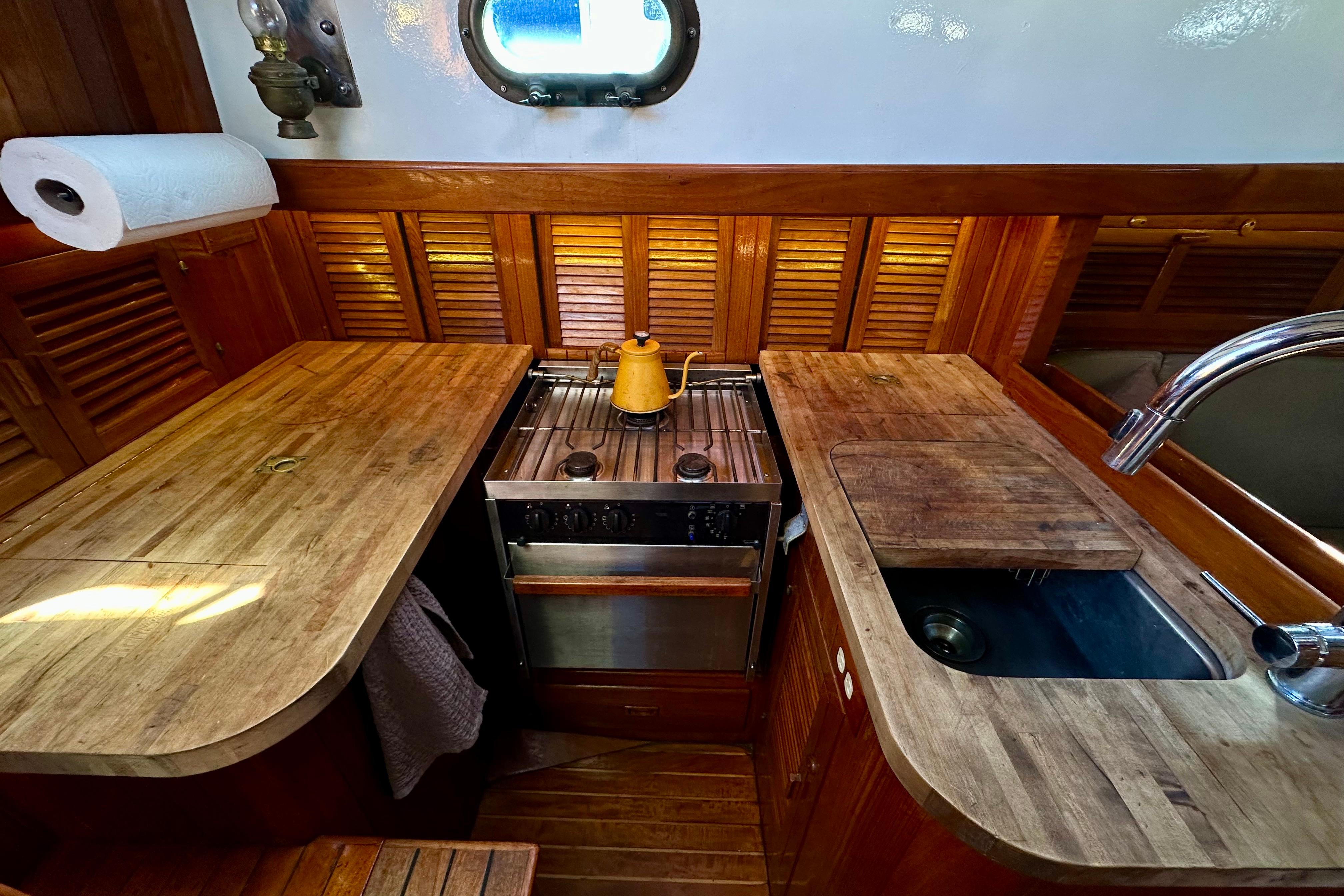 1978 Tayana 37 yacht galley with wooden countertops, stove, and sink.