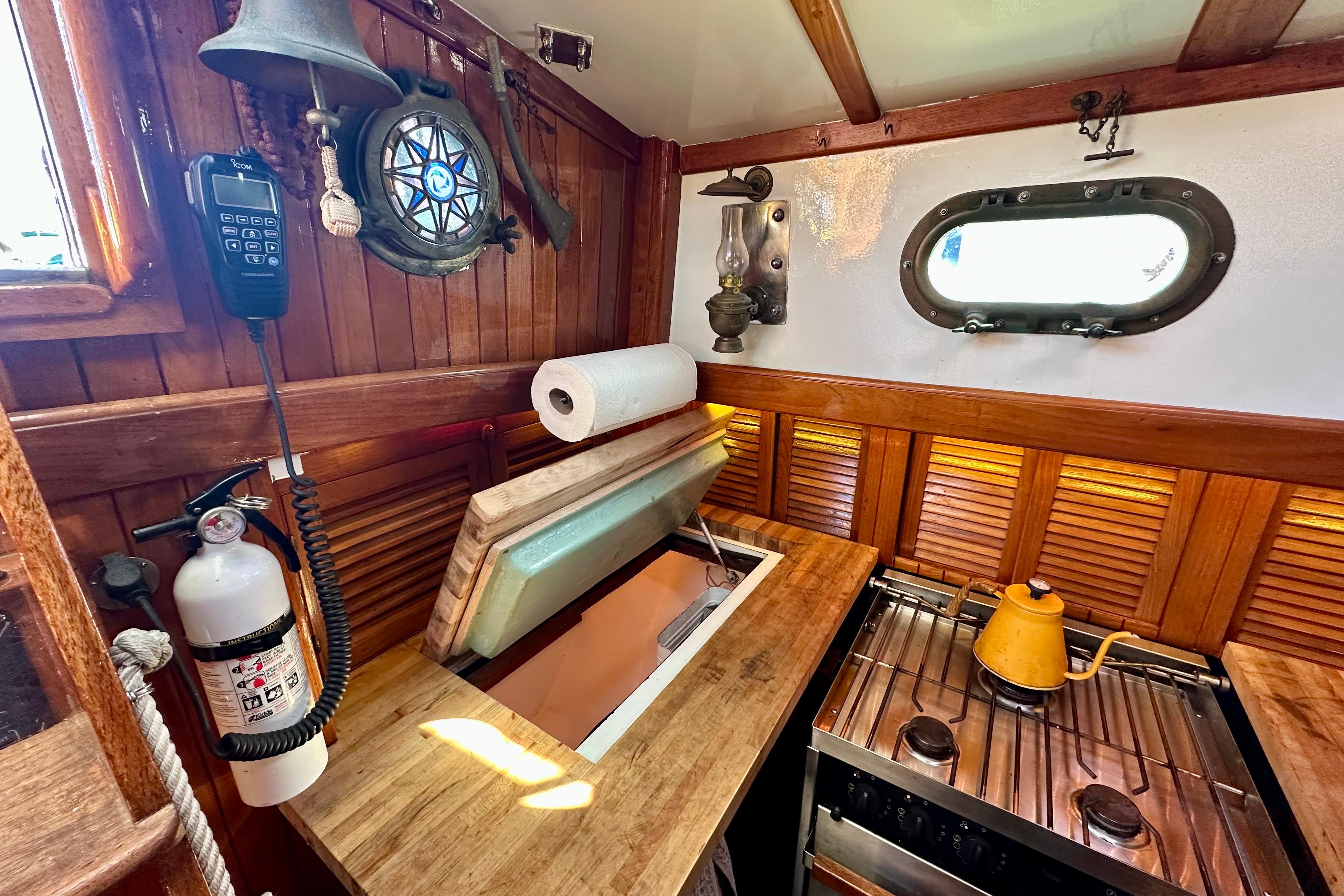 Interior of 1978 Tayana 37 sailboat galley with wooden finish and vintage decor.