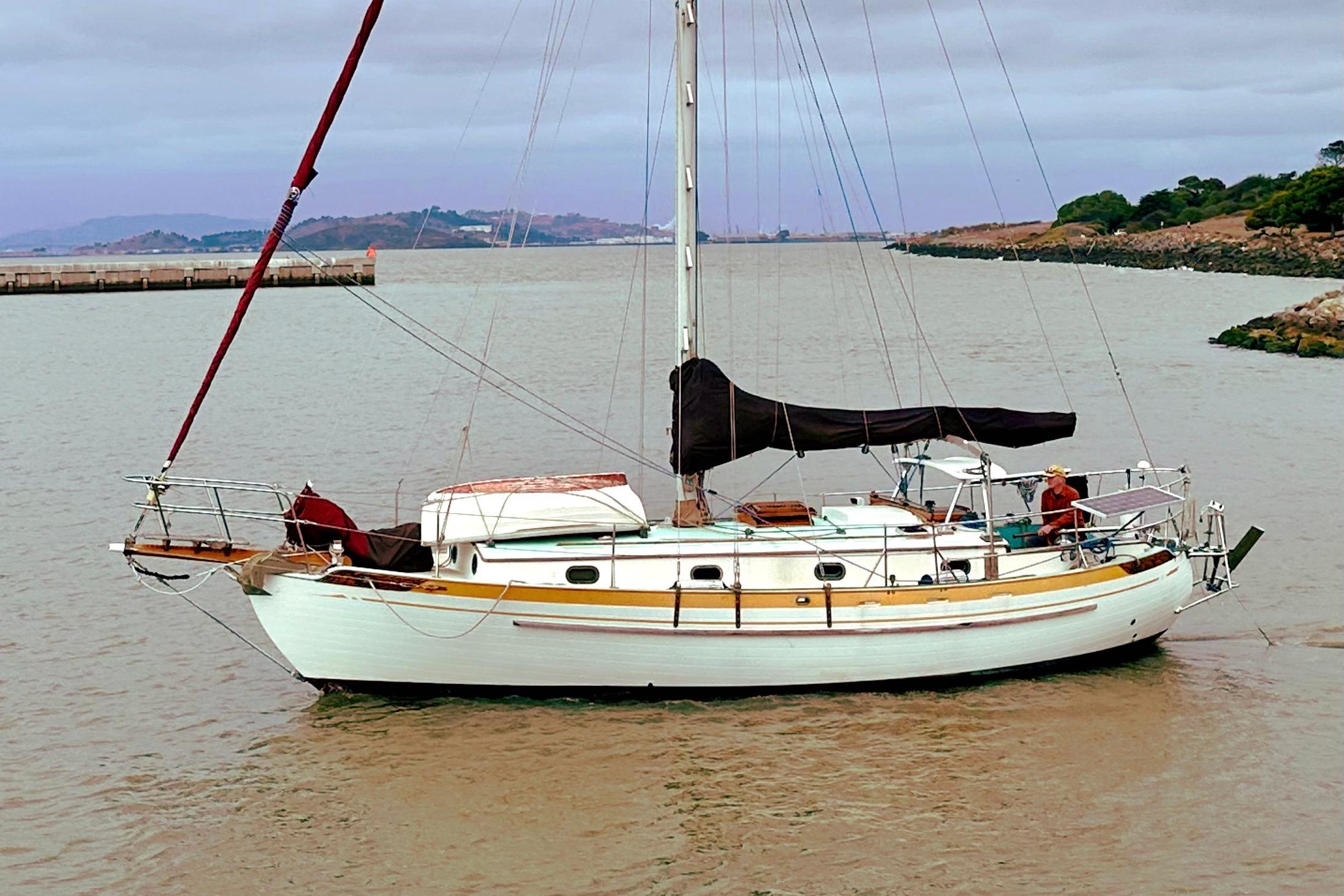 1978 Tayana 37 sailboat anchored in a calm bay with scenic background.