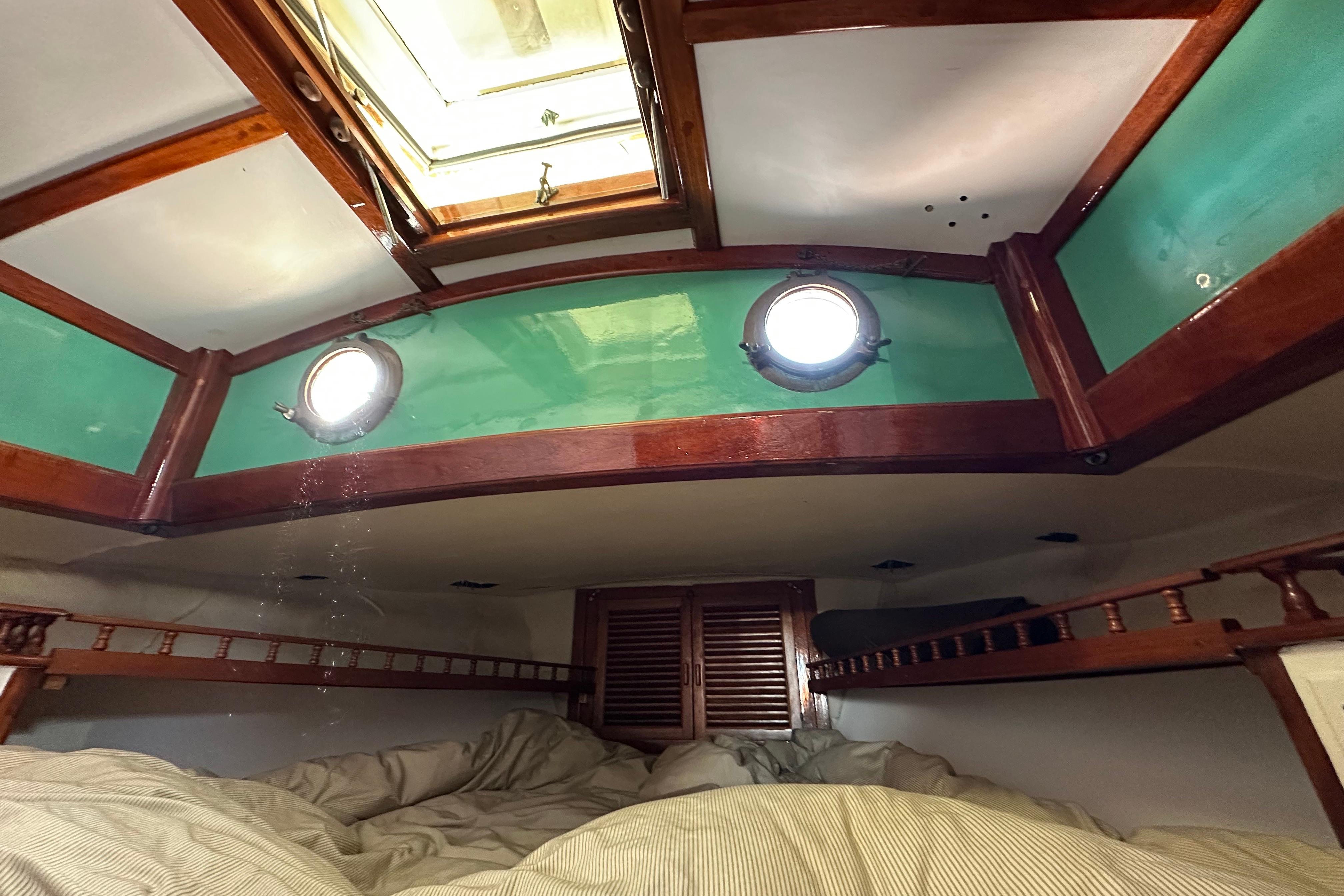 Cozy cabin interior of 1978 Tayana 37 sailboat with wooden accents and portholes.