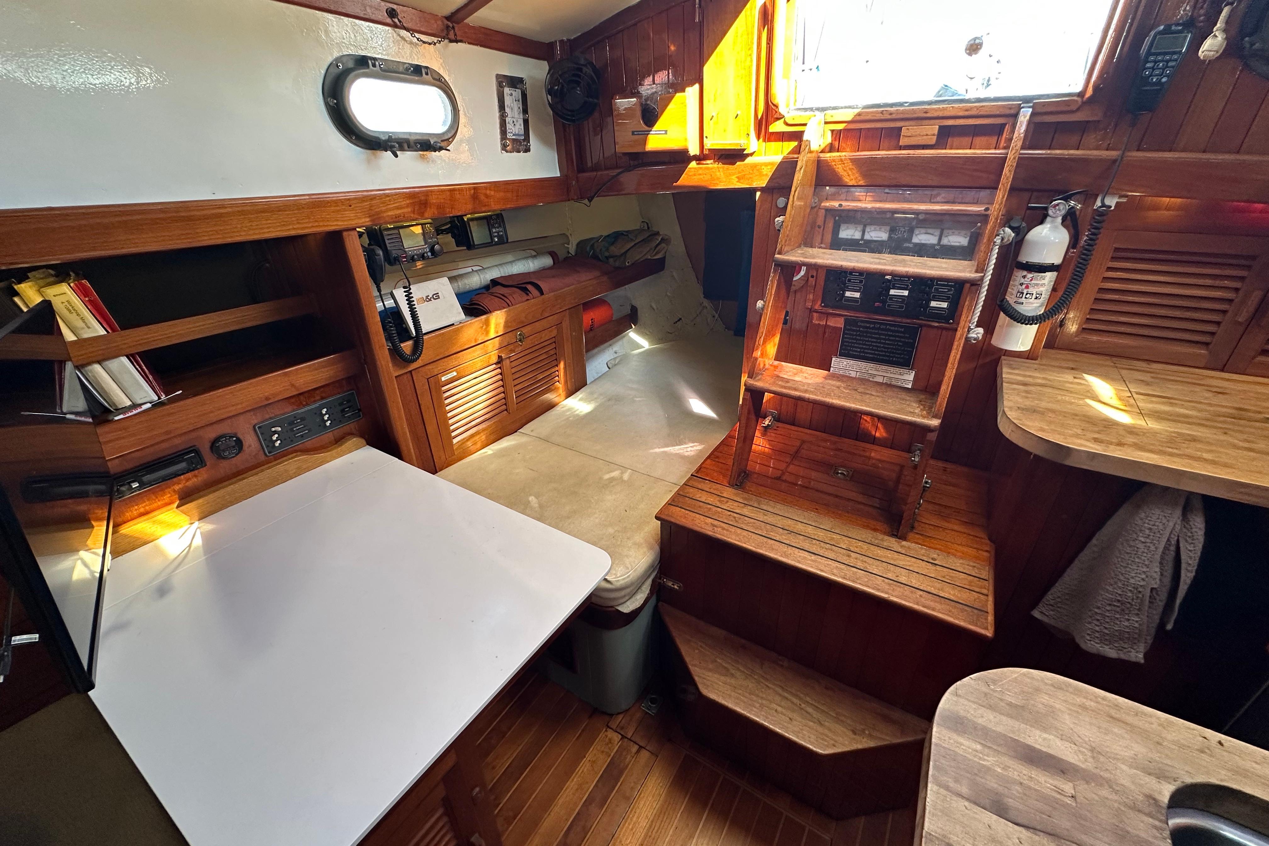 1978 Tayana 37 sailboat interior with wooden cabinetry, navigation table, and ladder.