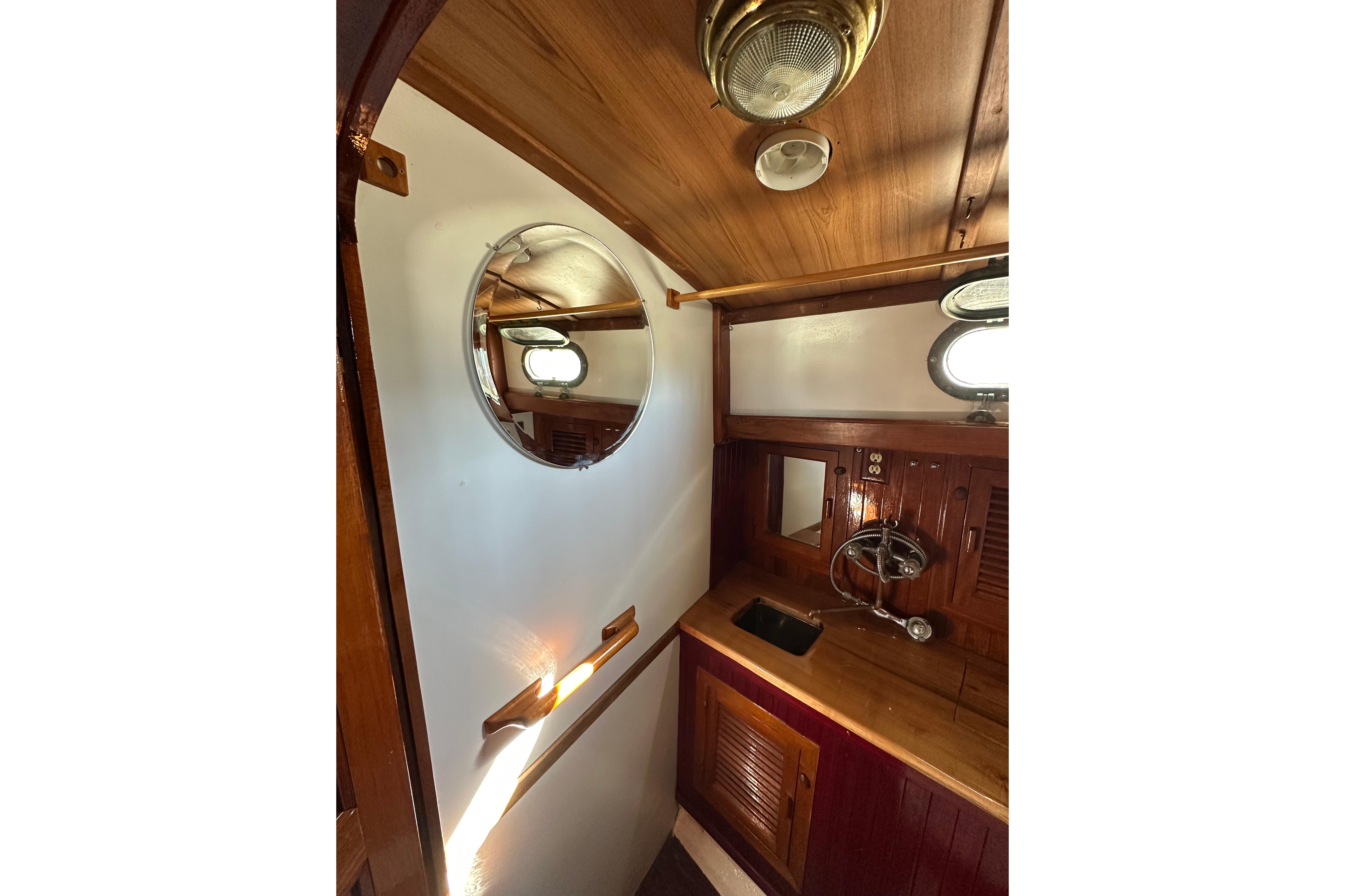 1978 Tayana 37 yacht interior with wooden cabinetry and round mirror.