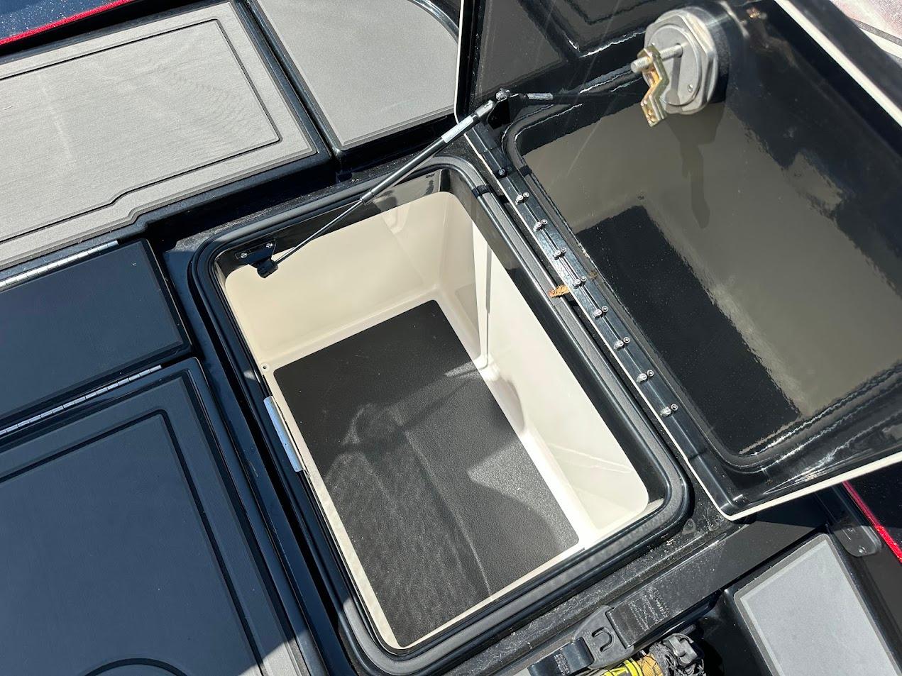 Open storage compartment on 2024 Caymas XS 20 boat, showcasing interior space and latch mechanism.