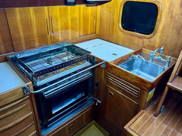 Vintage 1974 Nautor Swan 38 yacht kitchen with wood cabinetry, stove, and sink.