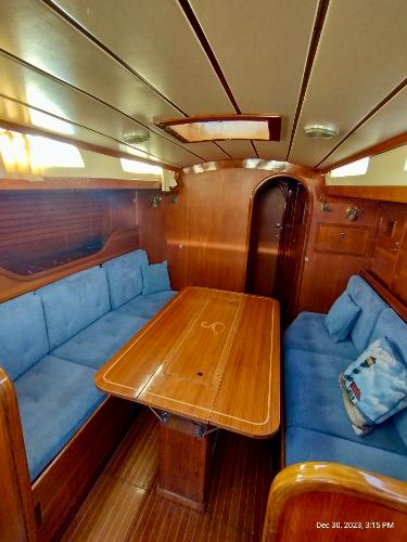 Interior of 1974 Nautor Swan 38 sailboat with wooden table and blue seating.