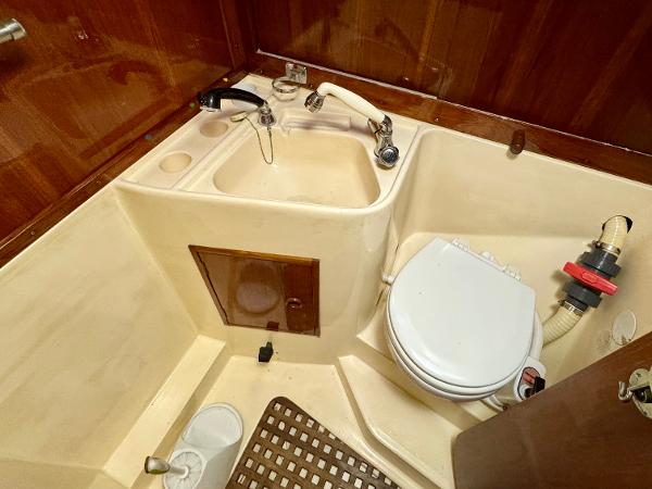 1974 Nautor Swan 38 yacht bathroom with sink, toilet, and wooden accents.