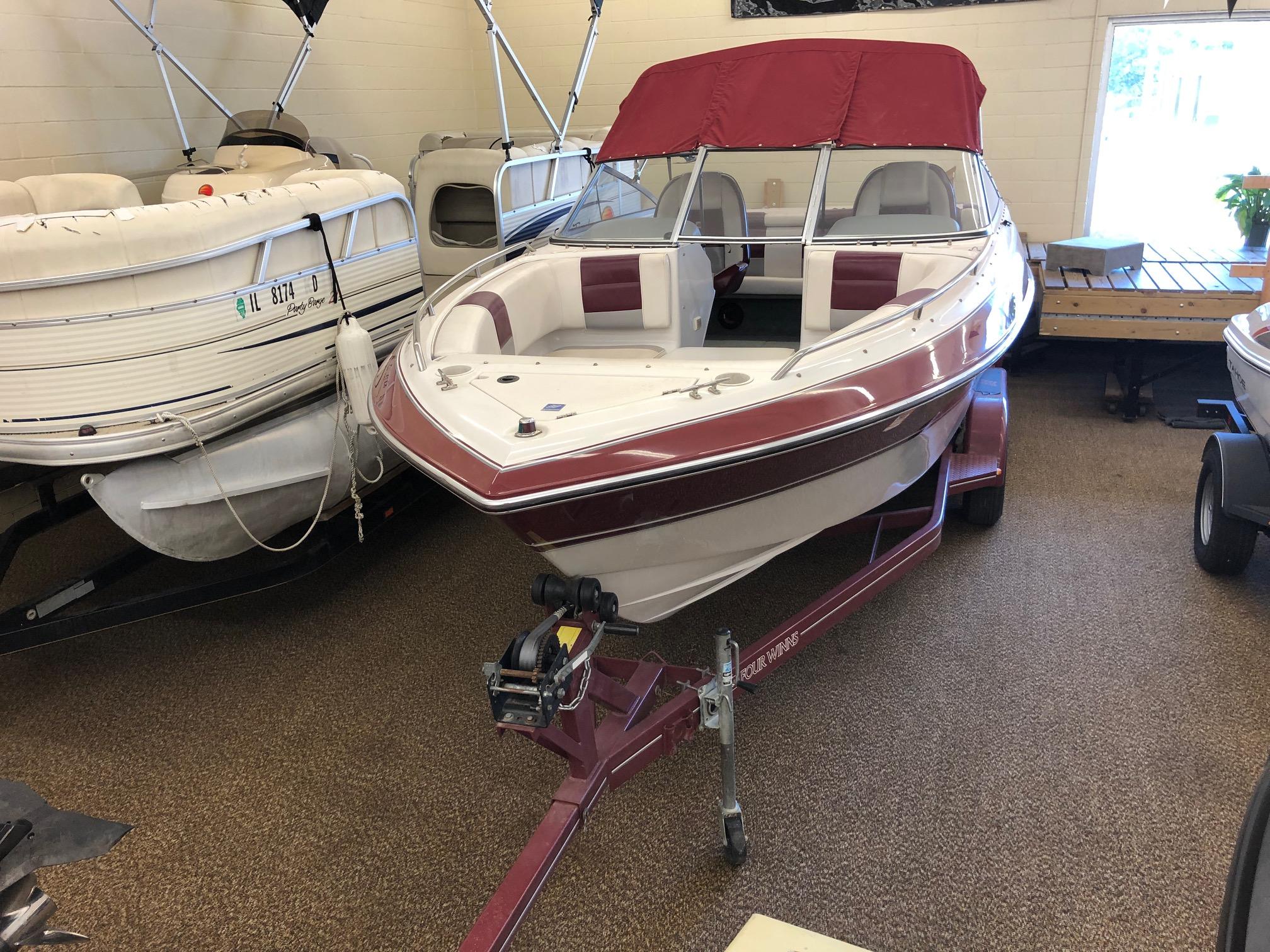 1992 Four Winns 220 Horizon Open Bow boat with maroon accents on trailer in showroom.