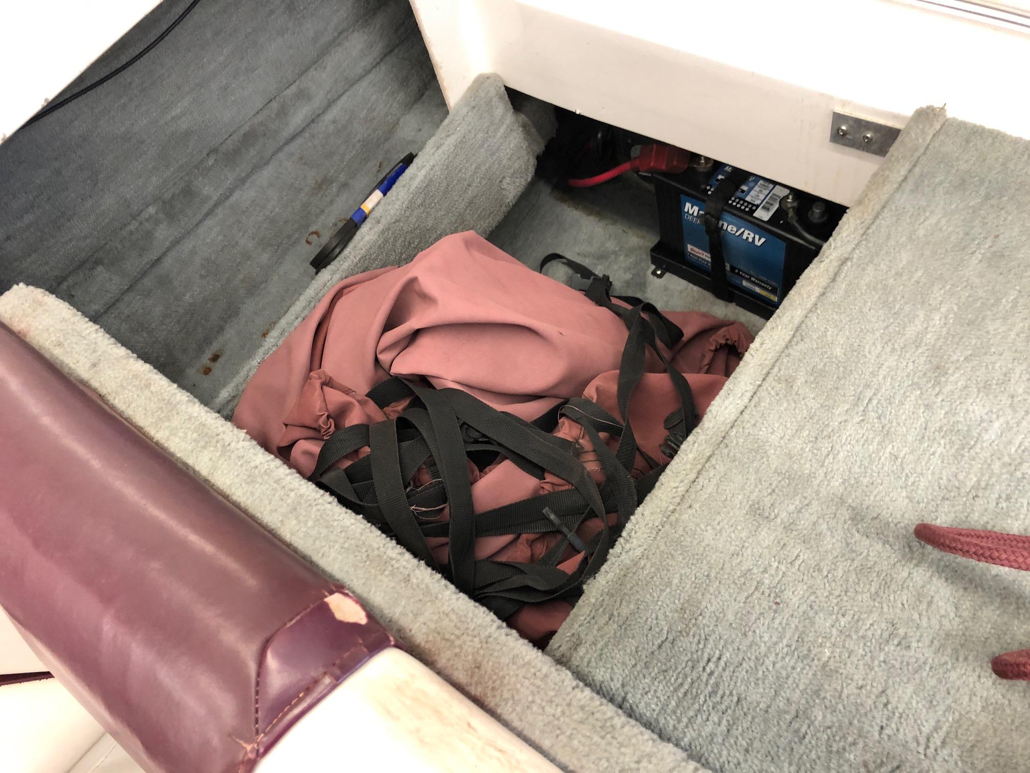 Storage compartment of a 1992 Four Winns 220 Horizon Open Bow boat with battery and gear.