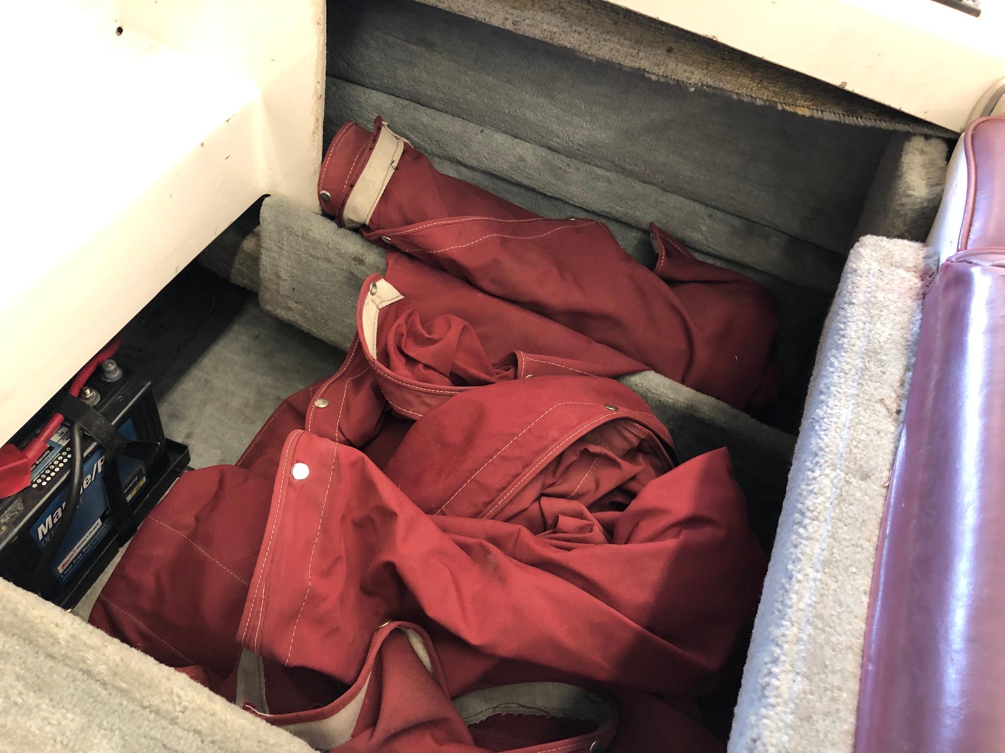 Storage compartment of 1992 Four Winns 220 Horizon Open Bow with red canvas covers.