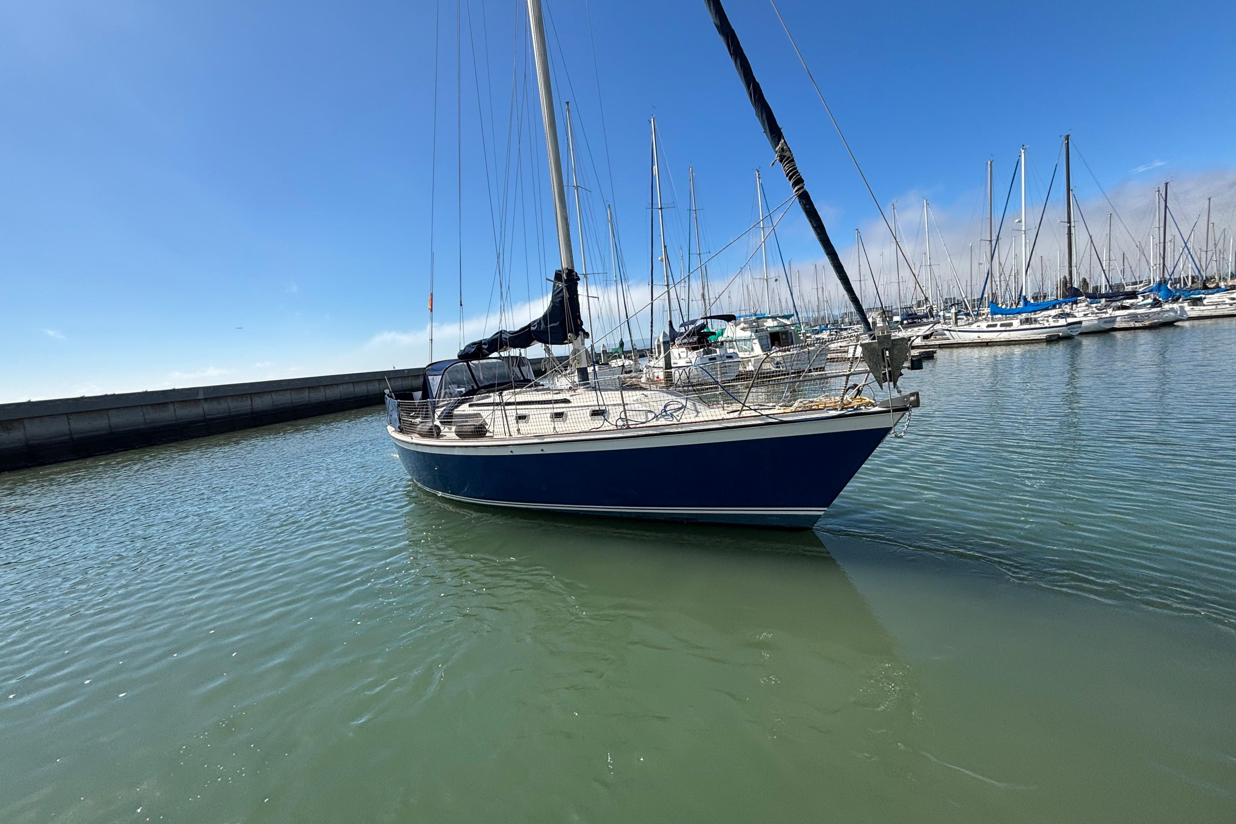 1981 O'Day 34 sailboat docked in a marina under clear blue skies.
