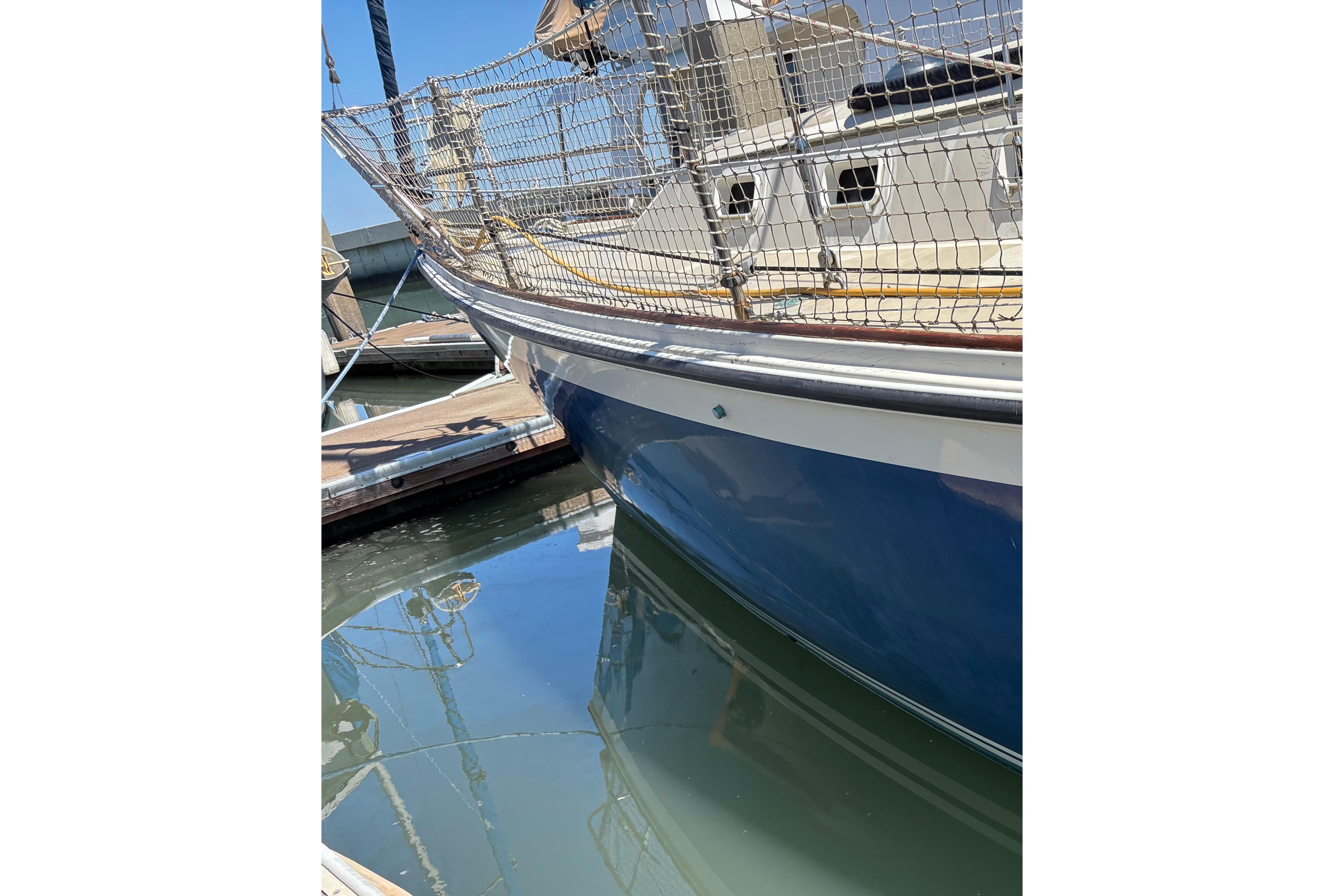 1981 O'Day 34 sailboat docked, blue hull reflecting in calm marina water.