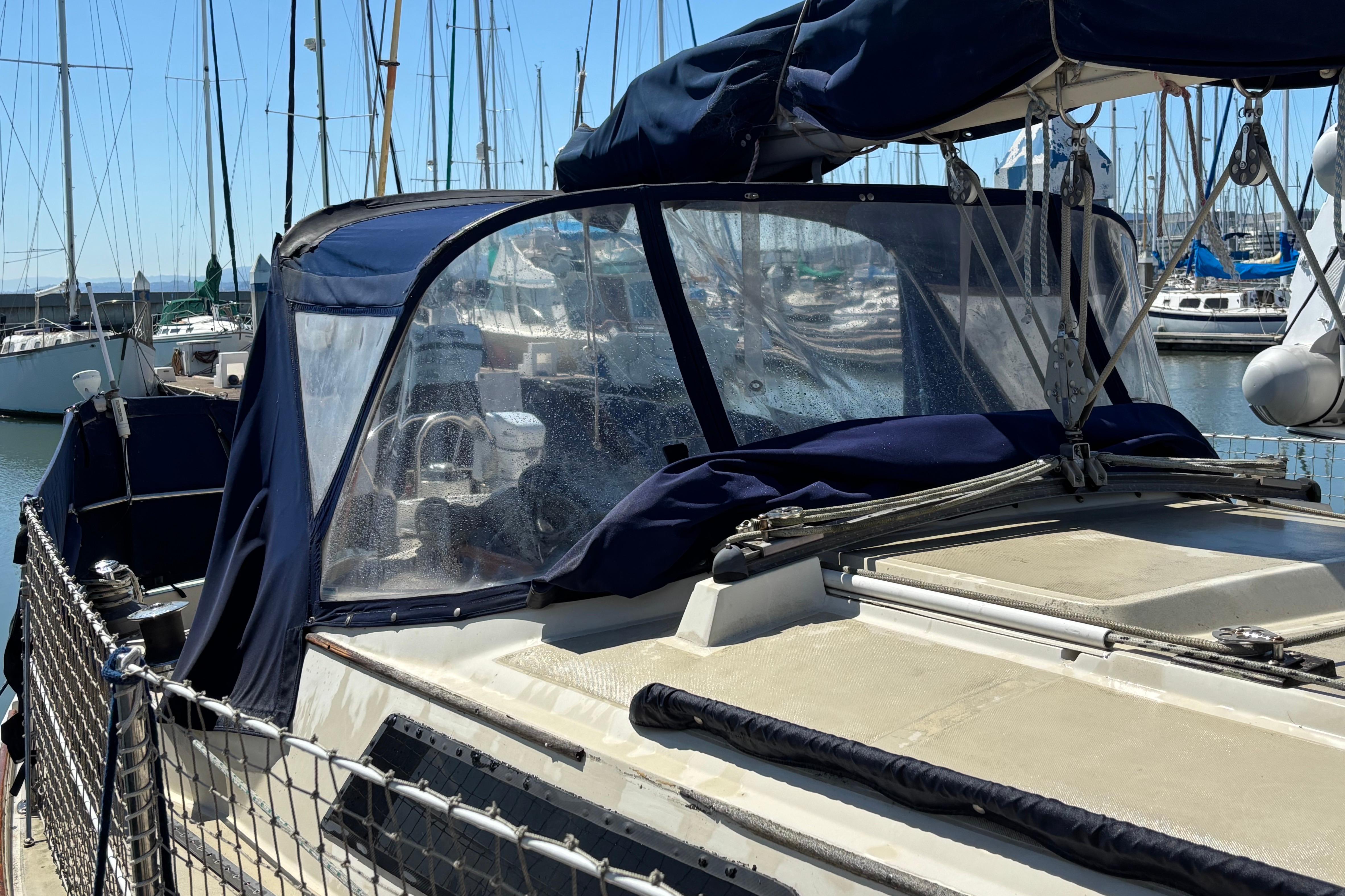 1981 O'Day 34 sailboat with blue canvas cover docked in marina.