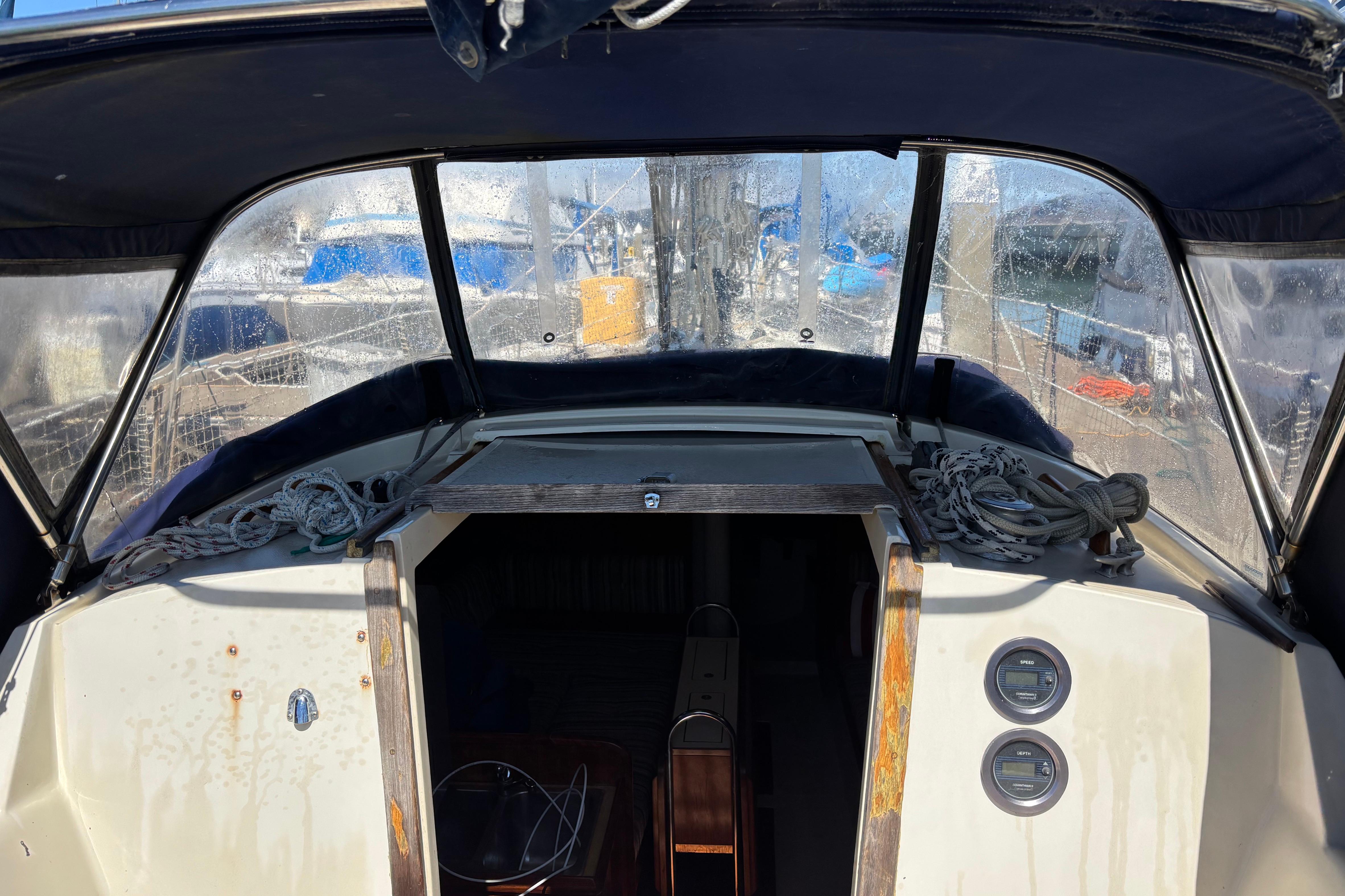 1981 O'Day 34 sailboat cockpit with ropes and gauges, marina view through windows.