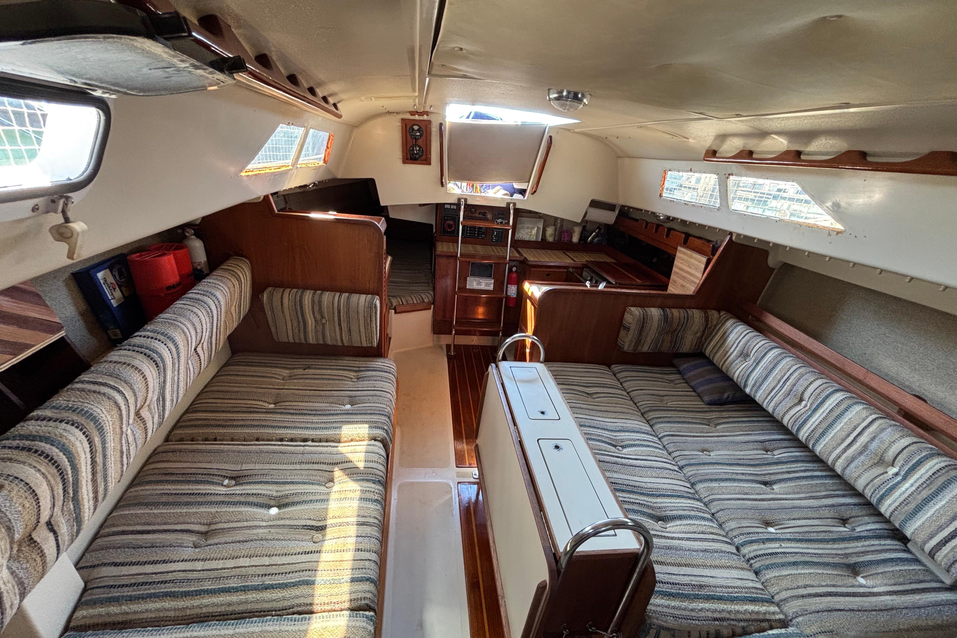 Interior of 1981 O'Day 34 sailboat with striped upholstery and wooden accents.