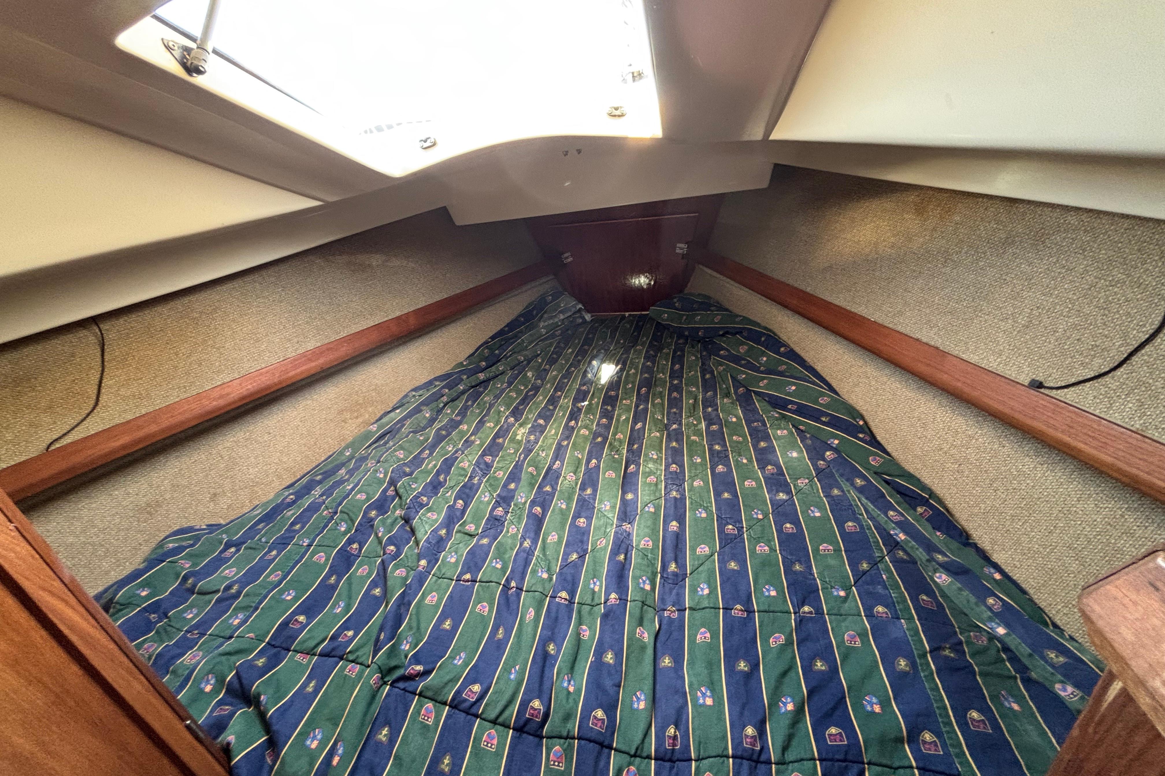 Cozy cabin interior of 1981 O'Day 34 sailboat with patterned bedding.