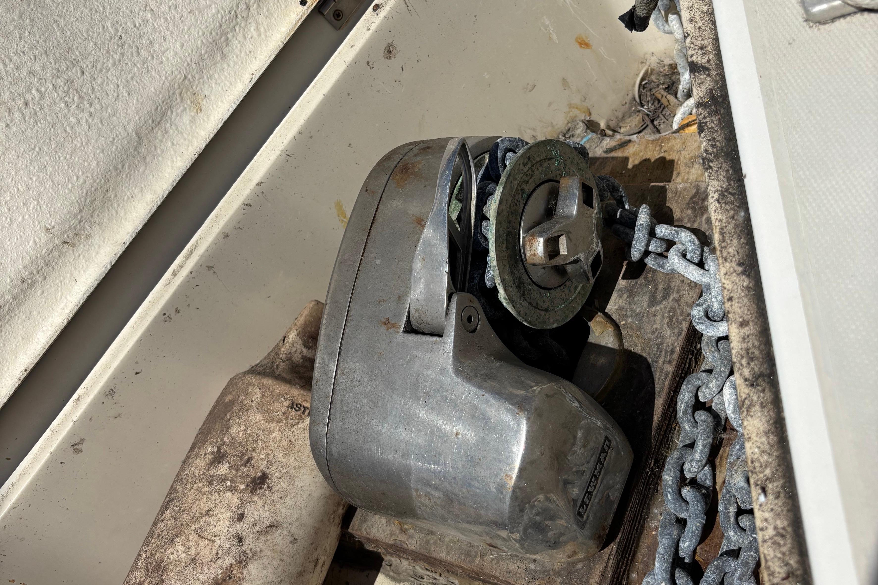 Anchor windlass on 1981 O'Day 34 sailboat with chain and weathered surfaces.