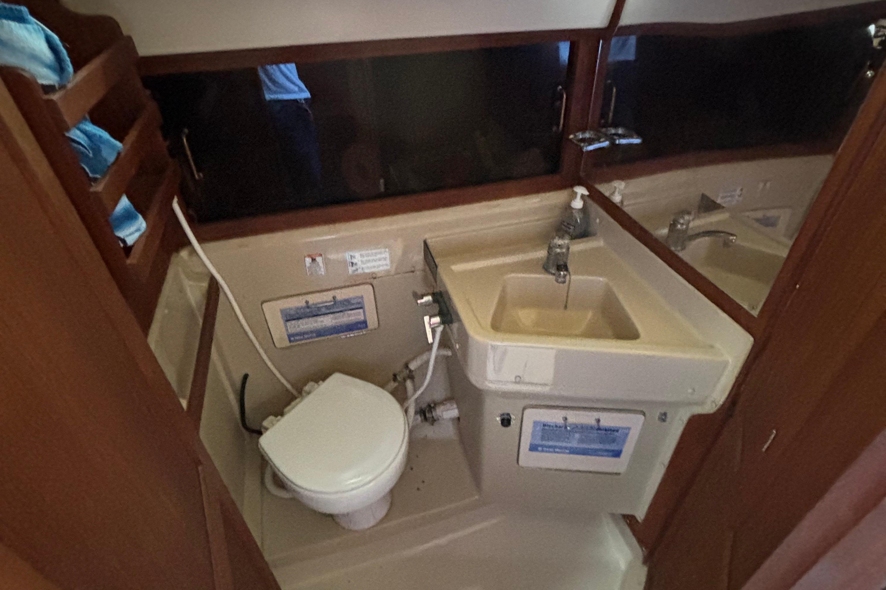 1981 O'Day 34 yacht bathroom with sink, toilet, and wooden shelving.