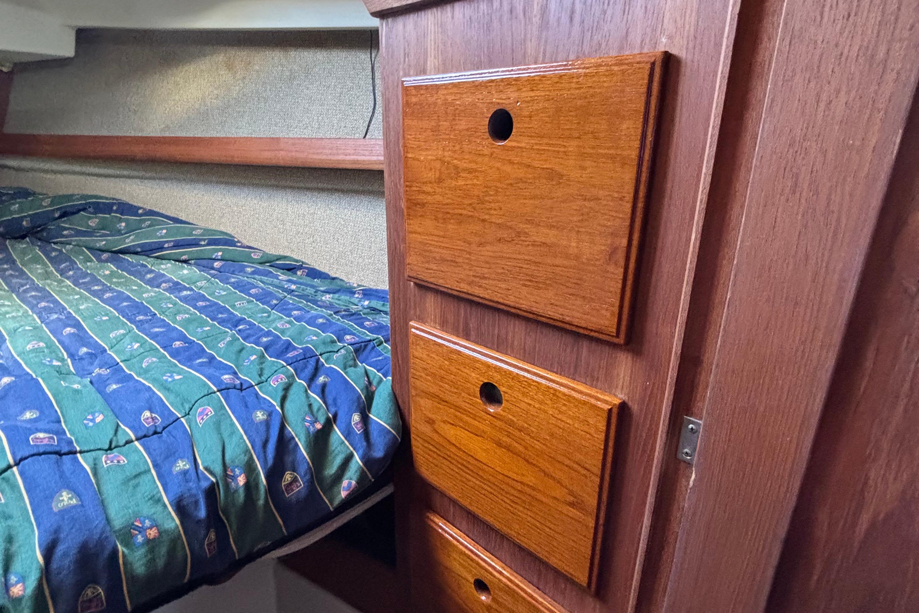 Interior of 1981 O'Day 34 sailboat with wooden drawers and patterned bedding.