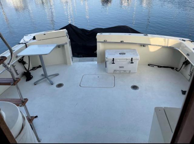 1978 Hatteras Sportfish boat deck with table and cooler, docked by calm water.